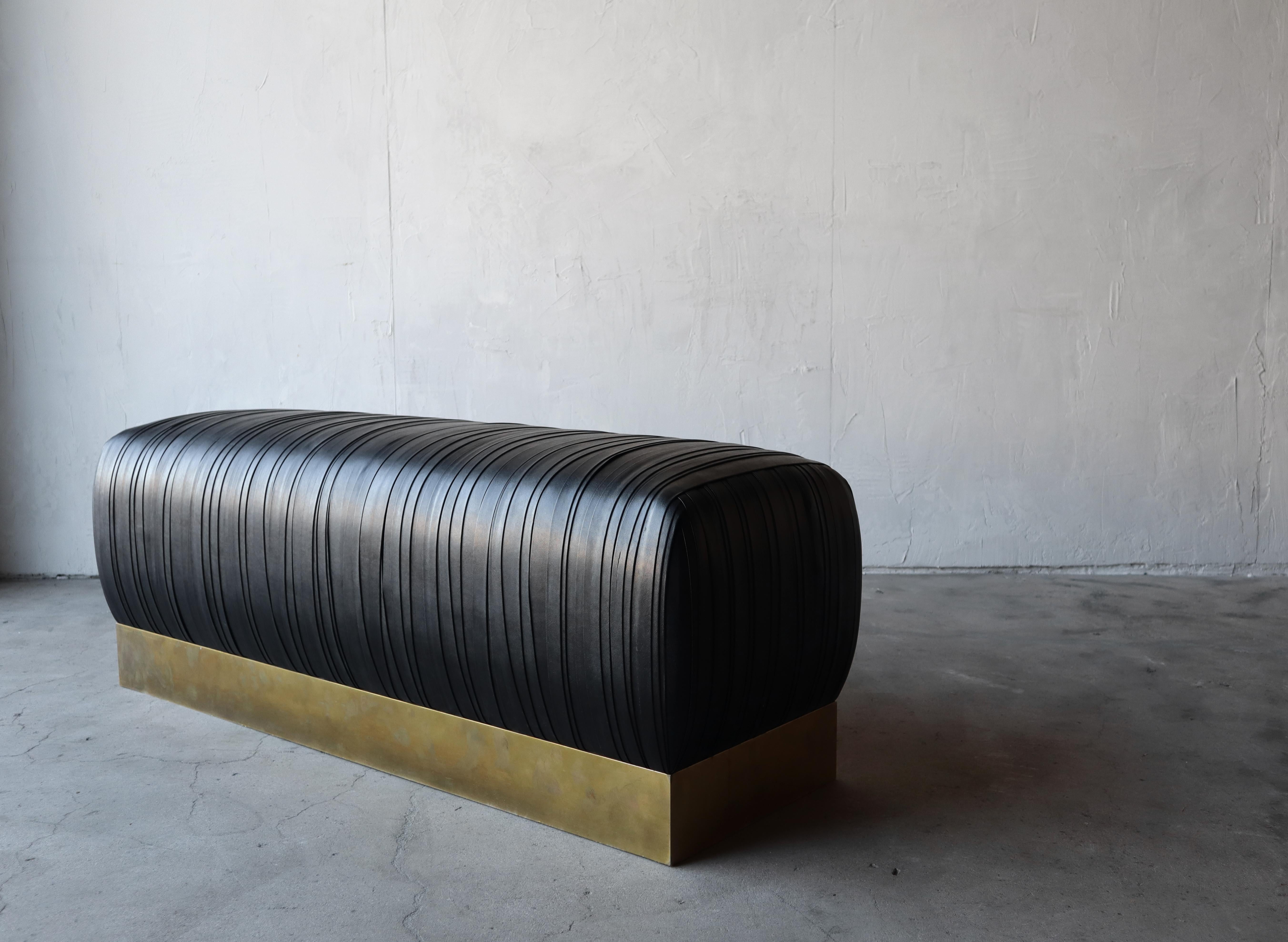 Stylish and substantial strapped black leather and faux patinated brass plinth bench. The bench is beautiful and would add so much class to any space. It would be perfect almost anywhere, entry, foot of a bed or as additional seating in any room,