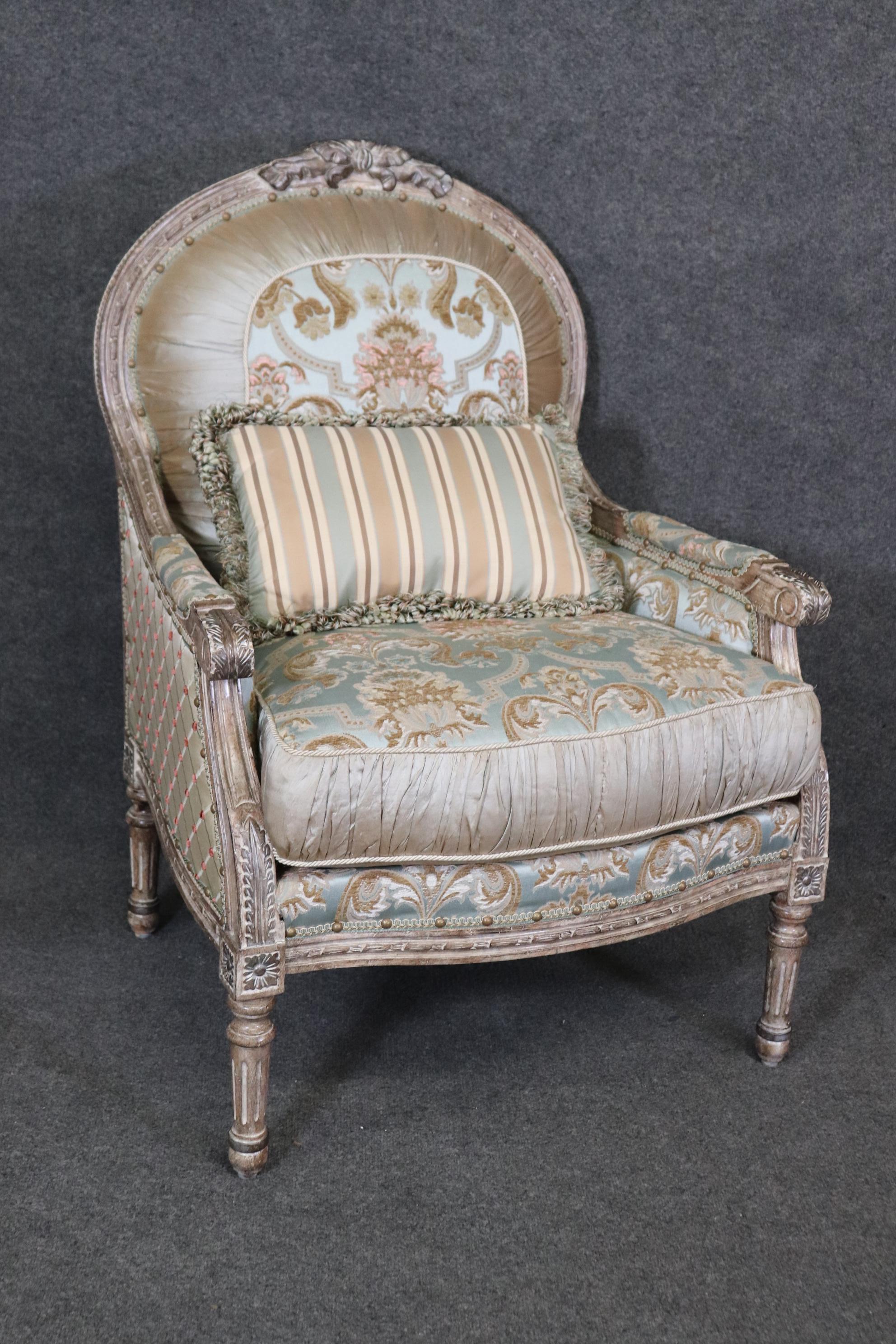 This is one of two pair available listed separately. This is a gorgeous pair of custom-upholstered French Louis bergere chairs or club chairs with gorgeous creme painted distressed finished frames and silver details on some of the carved areas. The