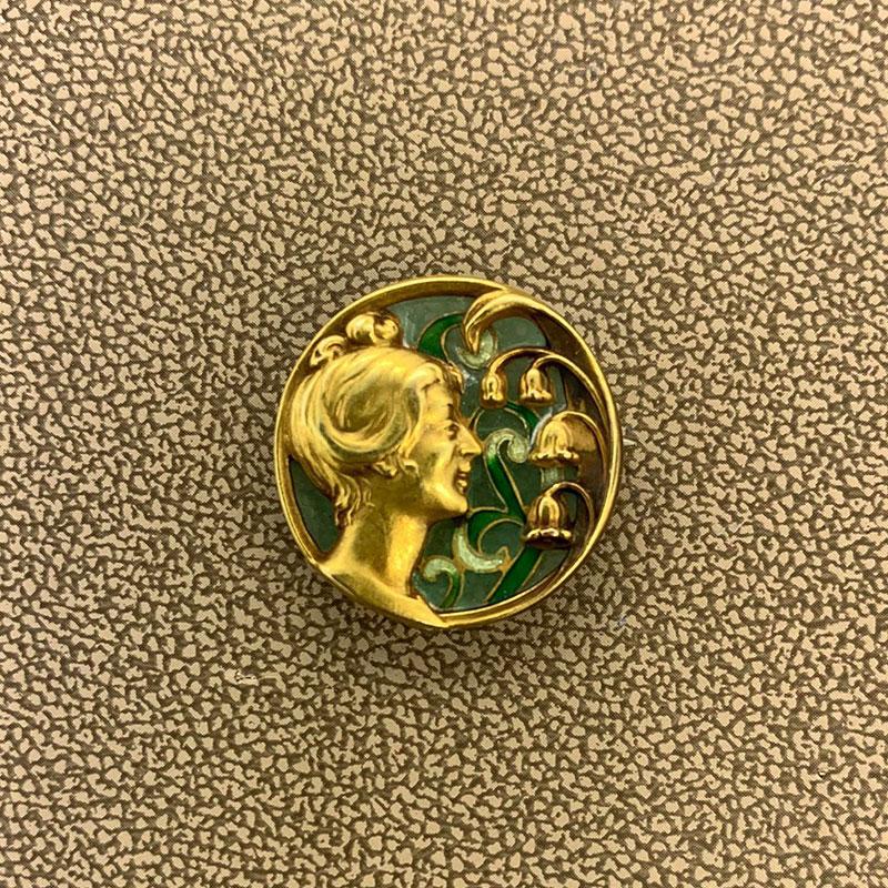 A lovely brooch made of enameled plique-à-jour. The happy woman looks onto her darling lily-of-the-valley flowers made of 14K yellow gold. This brooch doubles as pendant with the hidden hook on the backside.

Brooch Length: 0.80 inches

Brooch