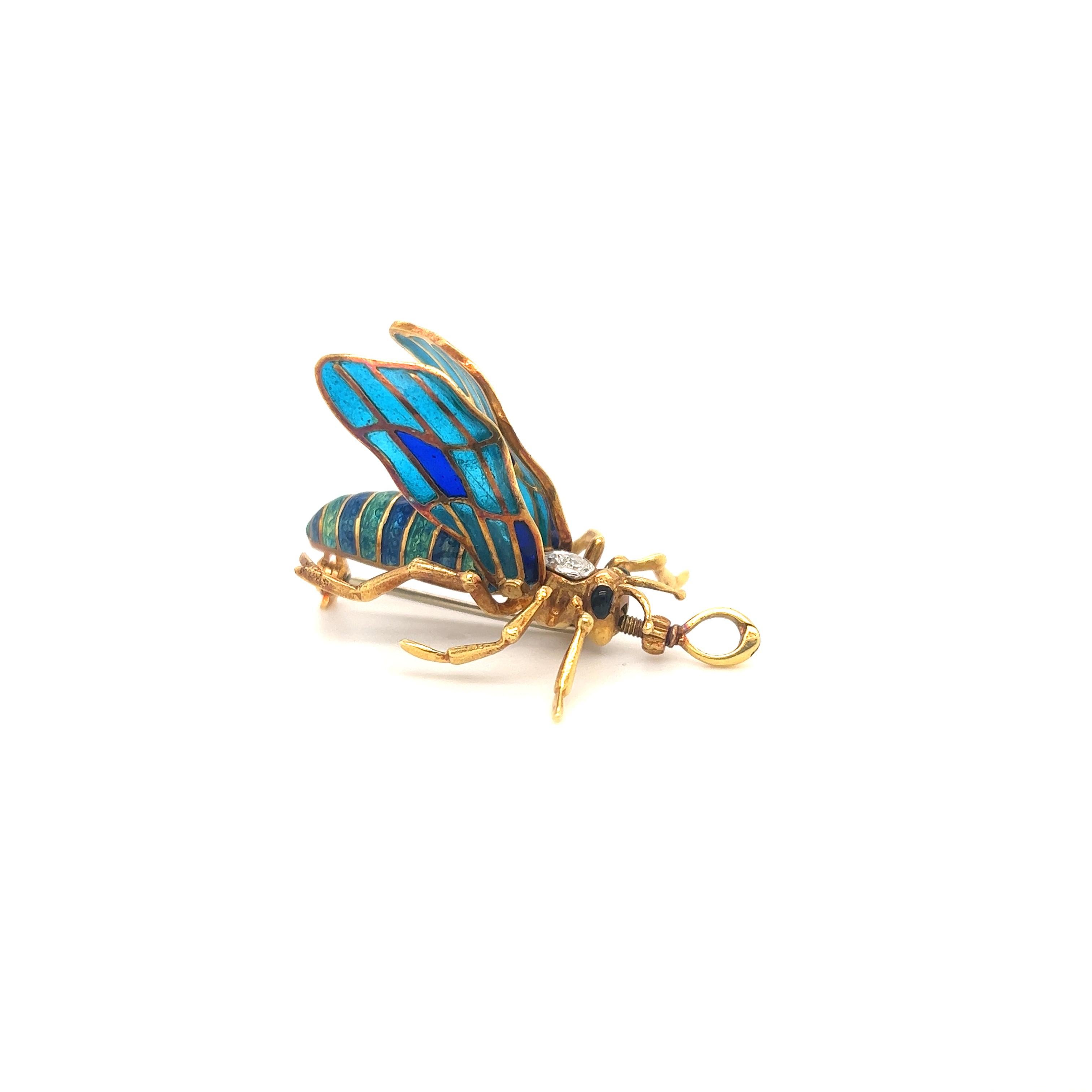 Beautiful design crafted in 18k yellow gold. The piece is a grasshopper with vibrant shades of green and blue guilloche enamel that decorate the body of the critter.  Details are endless as this little grasshopper looks extremely life like. The wing