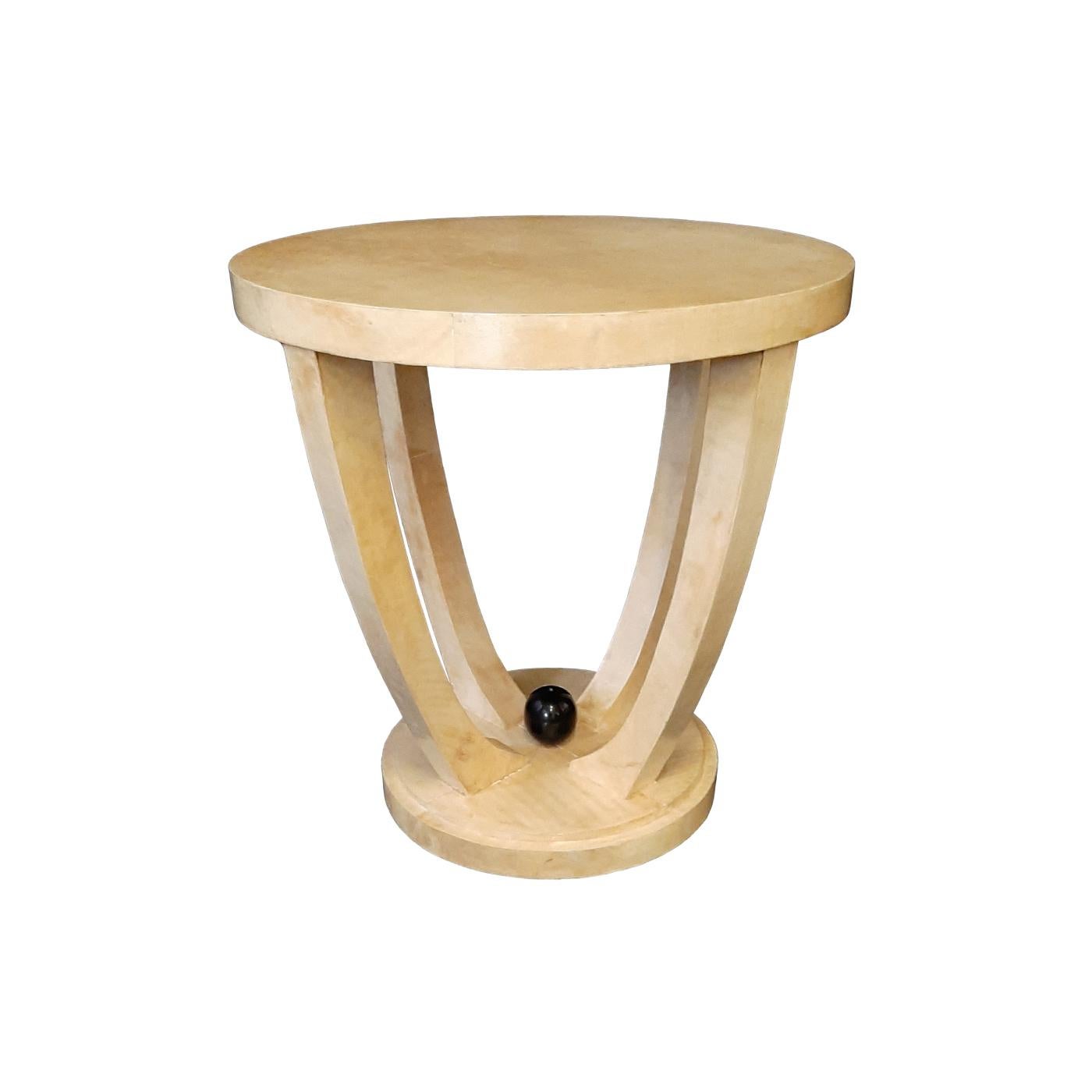 The singular aesthetic defining this round side table is thanks to its precious natural ivory parchment upholstery, which enables the piece to further upgrade its flair over time. Four legs curving outwards connect the base to the round top, the