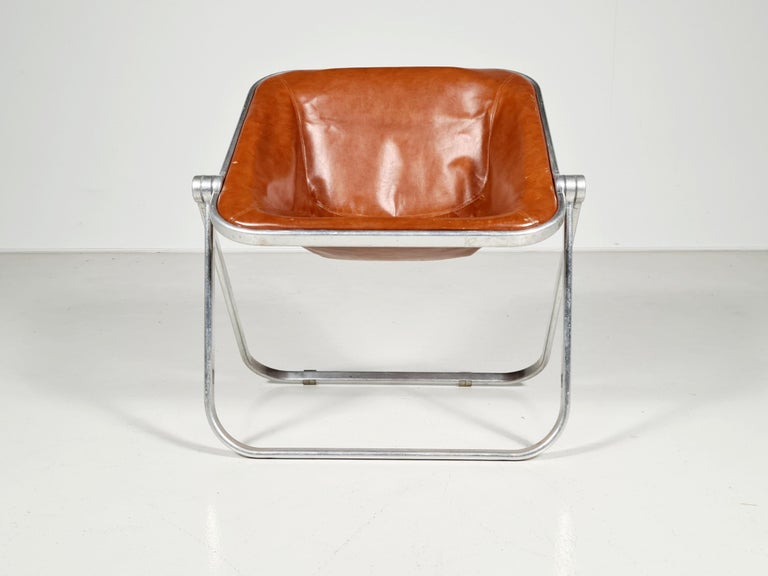 Acrylic Plona folding chair by Giancarlo Piretti for Castelli. The chair folds flat and can be placed against a wall or hung out of sight. Cognac leather original upholstery.

 This design is in the permanent collection of the MoMA.