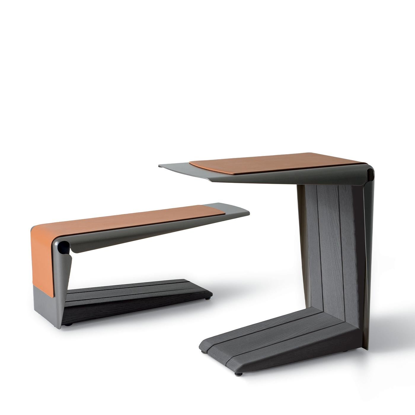 The Ploto coffee table features a painted metal structure with feet at the front and wheels at the rear. Solid ash wood inserts add natural texture inside the frame. The exterior is enhanced by a band of Pelle Plus or Satin leather paired with a