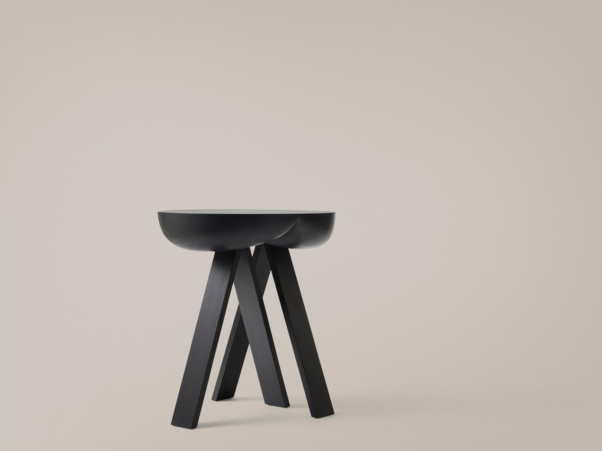 Side table designed by PlueerSmitt in 2014. 

Striking. Wooden side table consisting of two stripped-down trestles and a table top. The seemingly heavy top contrasts the rigid trestles. The top gives in and provides space for the sharp ends of the