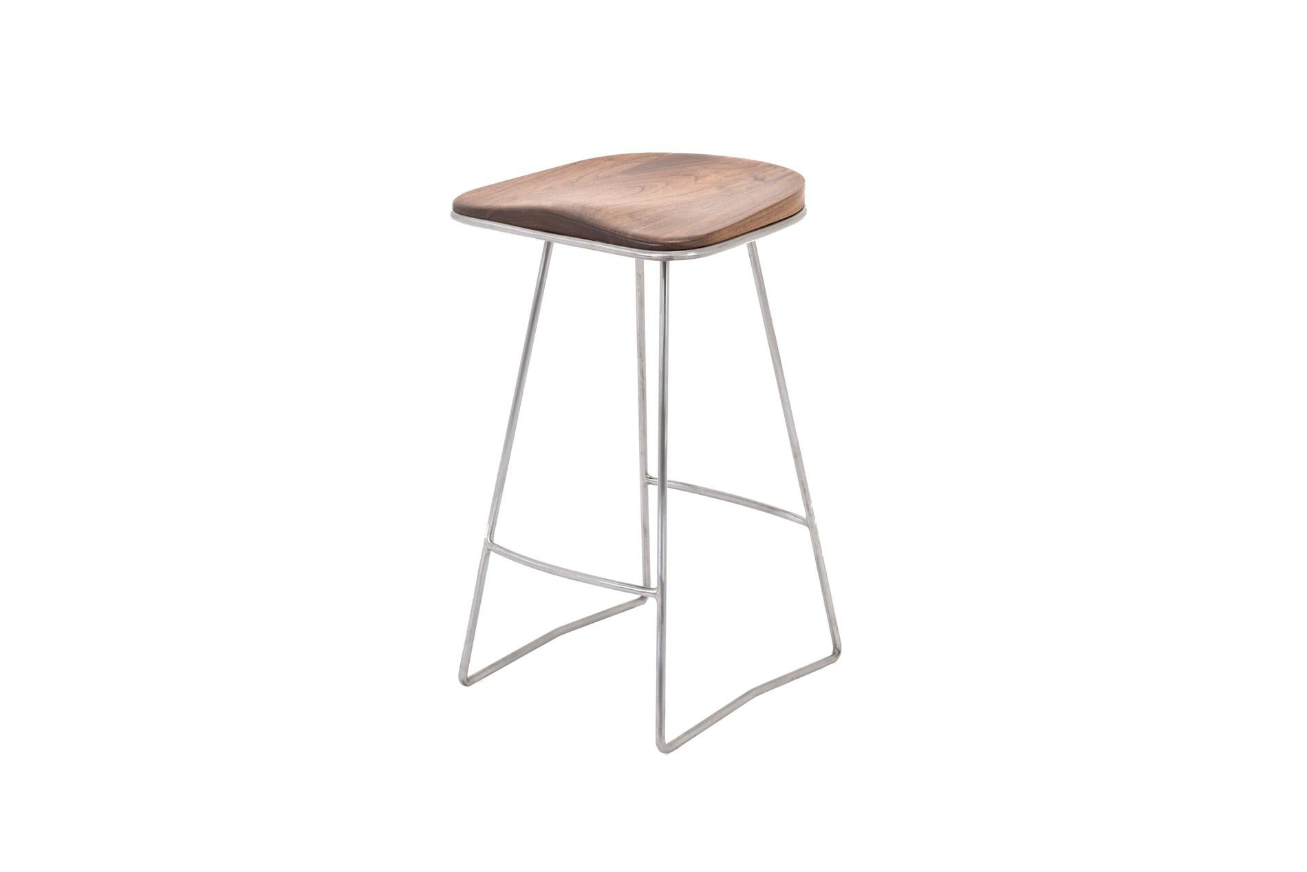 The Plug is a bar stool with an ergonomic shaped solid wood seat and a handcrafted steel frame. The shaped walnut seat enclosed in a signature metal frame is as relaxing as it is beautifully protected by the steel edge. The contour lines are soft to