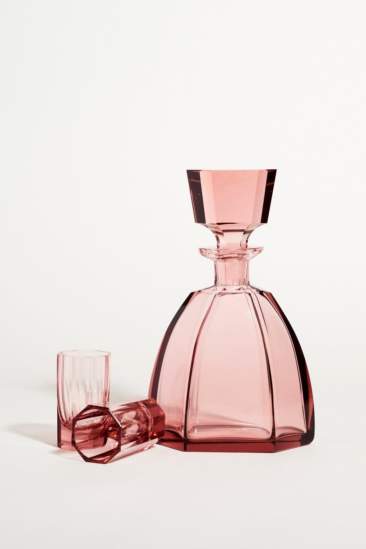 Beautiful Czech glass decanter in translucent plum pink, geometric shaping with a cut and polished hexagonal decanter and two octagonal glasses, square cut stopper reflects similar faceting in the glasses.