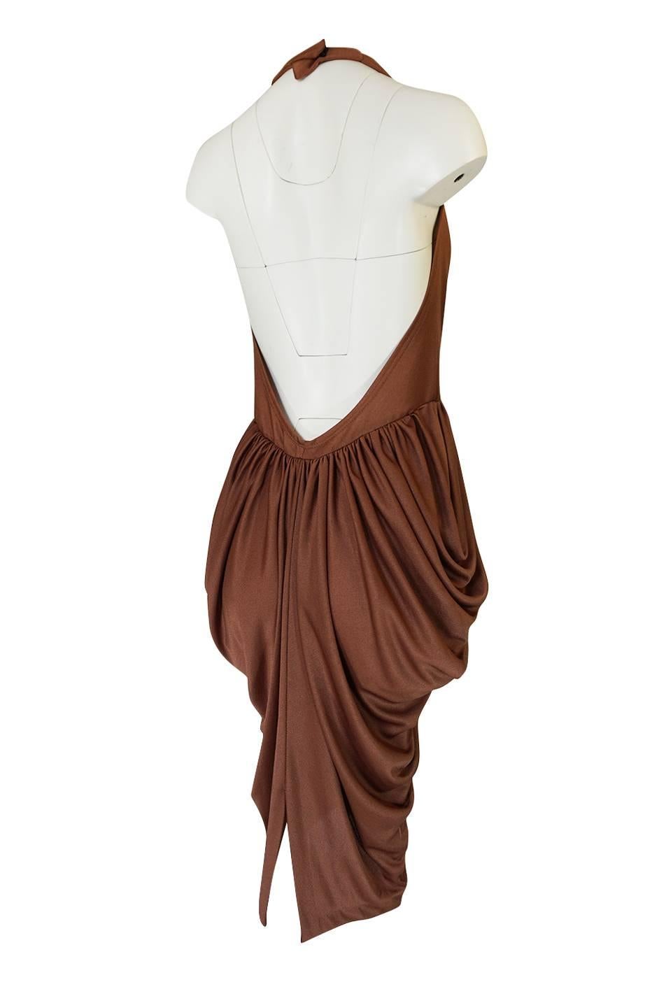 This dress is amazing. It is insanely sexy with a halter style front that plunges to just above the waist and has a back that is left completely open and bare. It is made of a liquid jersey in a deep taupe brown that feels amazing on. That fabric