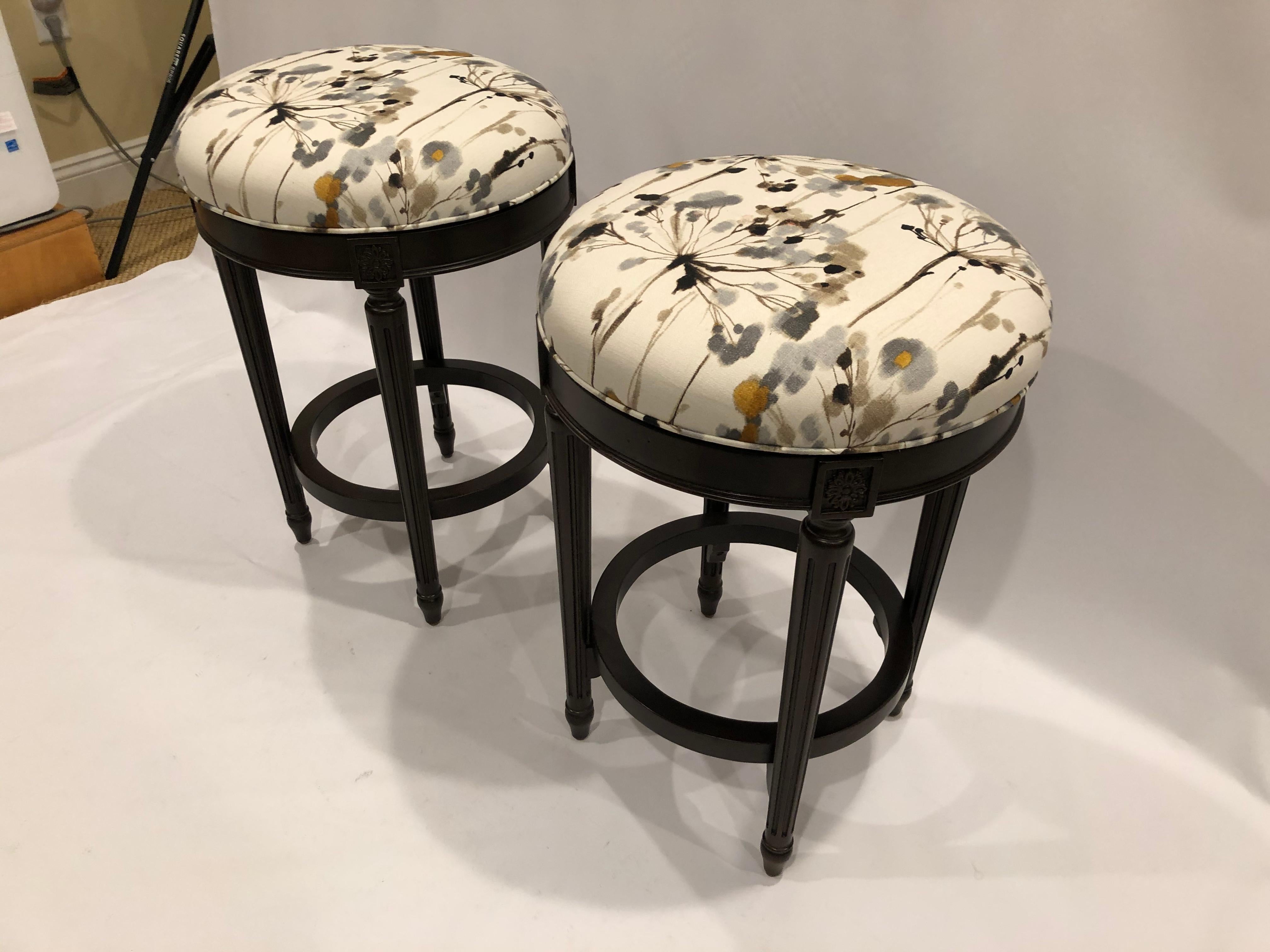 Plush well made ebonized wood counter stools having upholstered seats that swivel 360 degrees, and solid base with circular foot rest.
