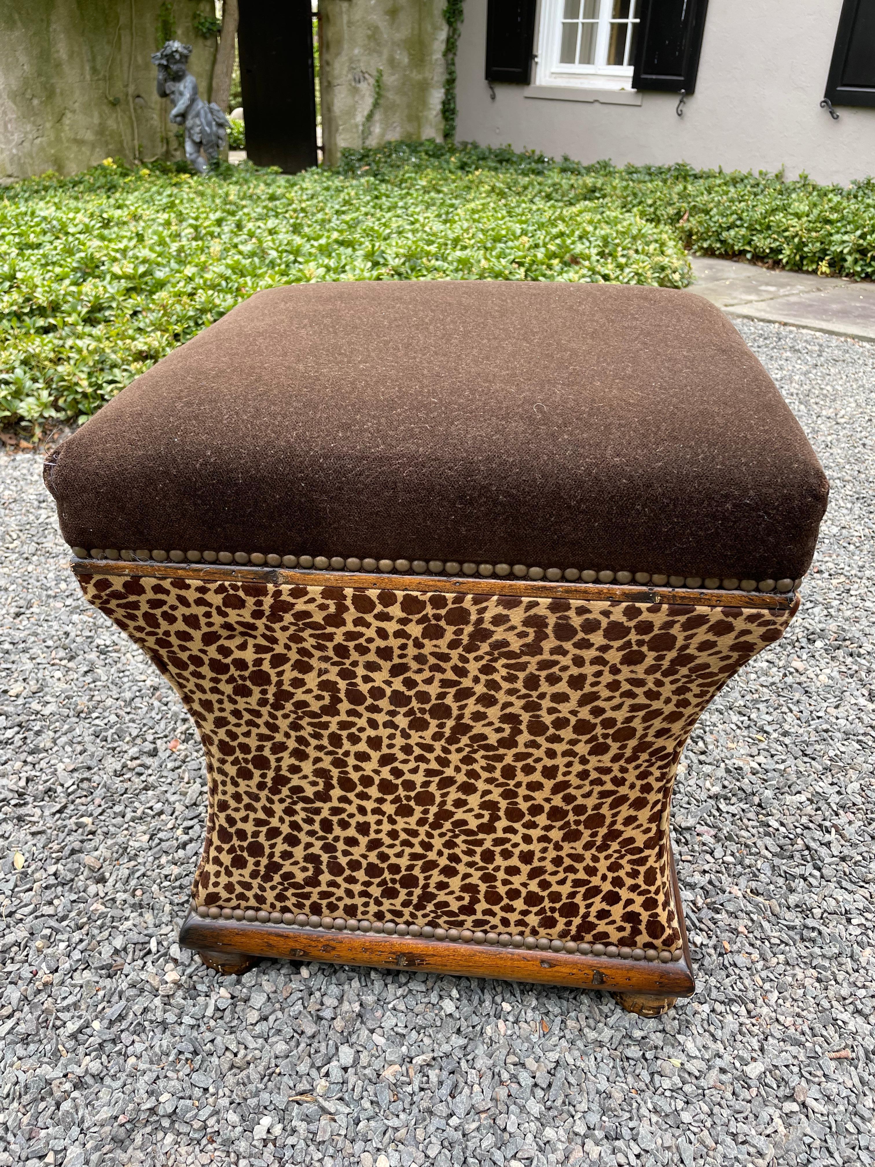 Glamorous pair of animal print ottomans with dark wood bases and bun feet. The tops are plush deep chocolate brown mohair and the bases are cowhide animal print with French brass nailhead trim.