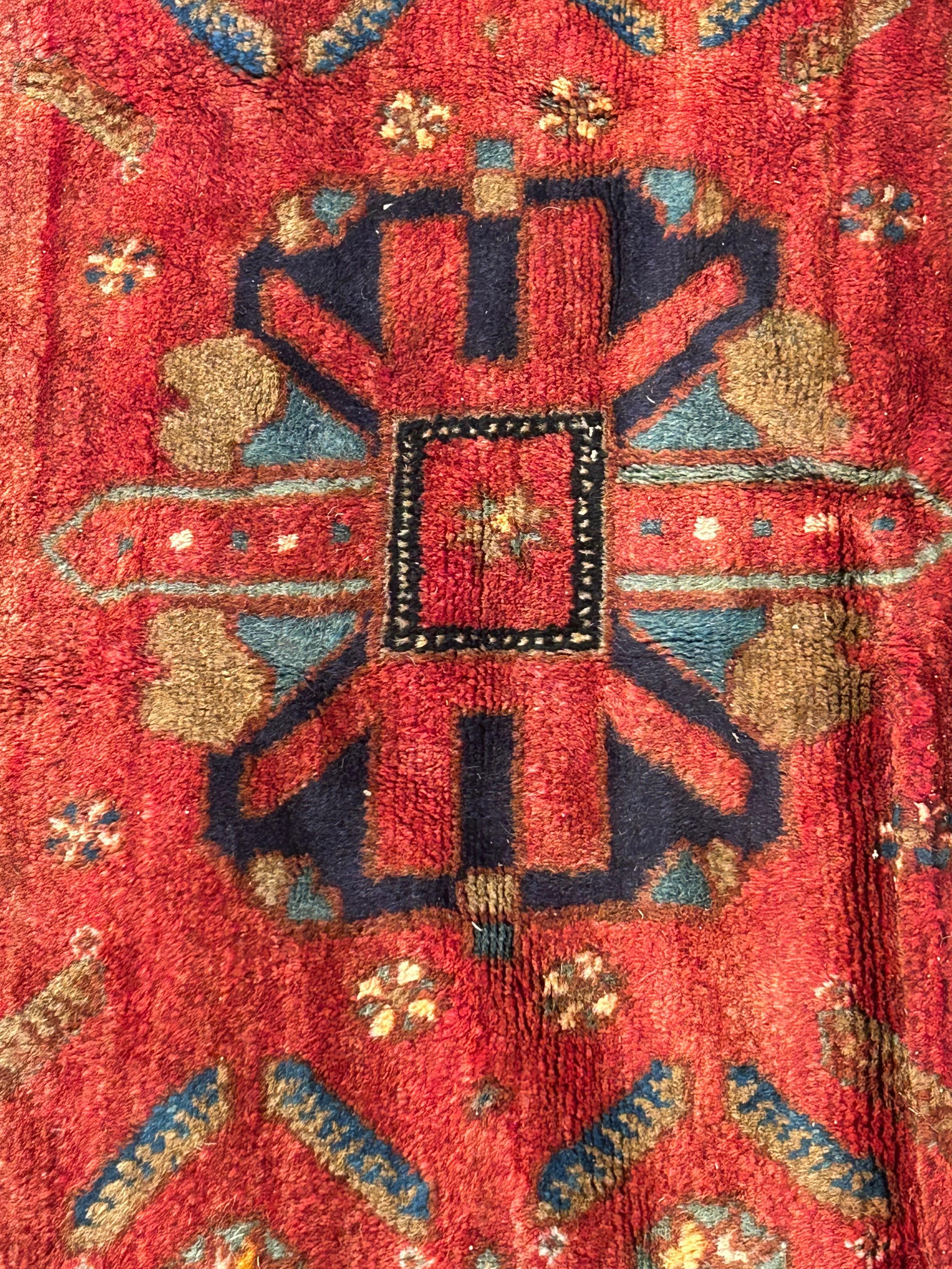 Preciosa alfombra vintage de felpa en tonos joya con ricos tonos azul marino y frambuesa .