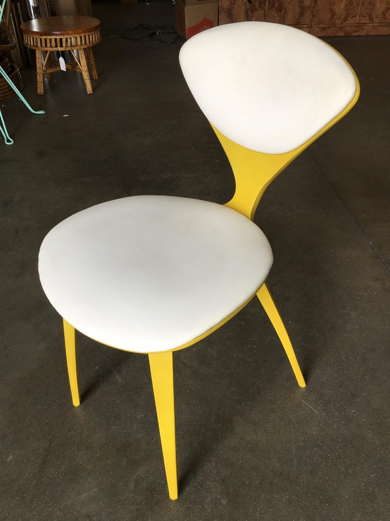 This is a set of 4 colorful chairs designed by Norman Cherner for Plycraft. Each chair is painted in its own unique color: red, green, blue, and yellow. They all have white cushions for the seat and back. The colors are original. 

This includes