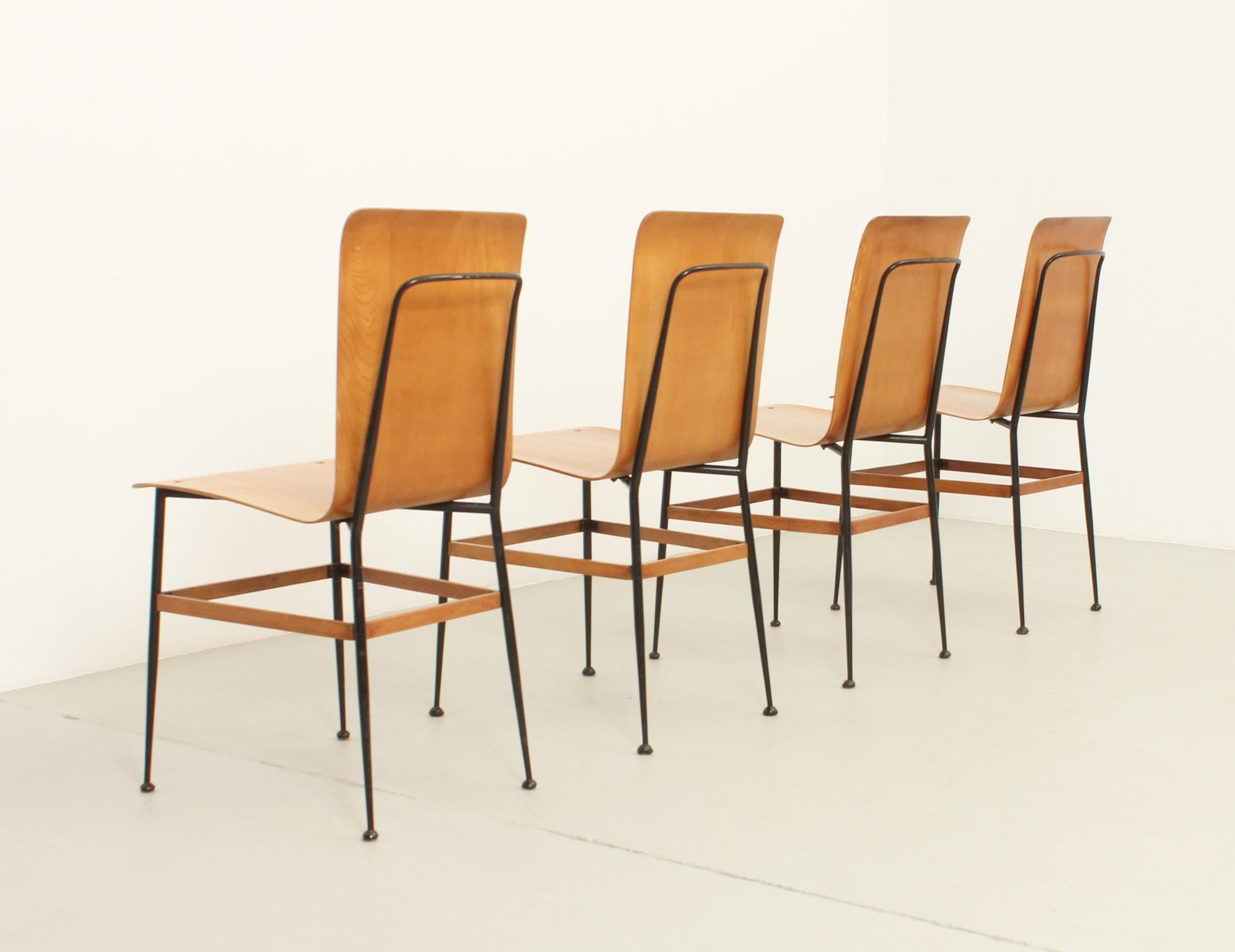 Four dining chairs designed in 1950s by Carlo Ratti and produced by Industria Legni Curvati, Italy. Plywood seat with black lacquered metal frame. Signed.