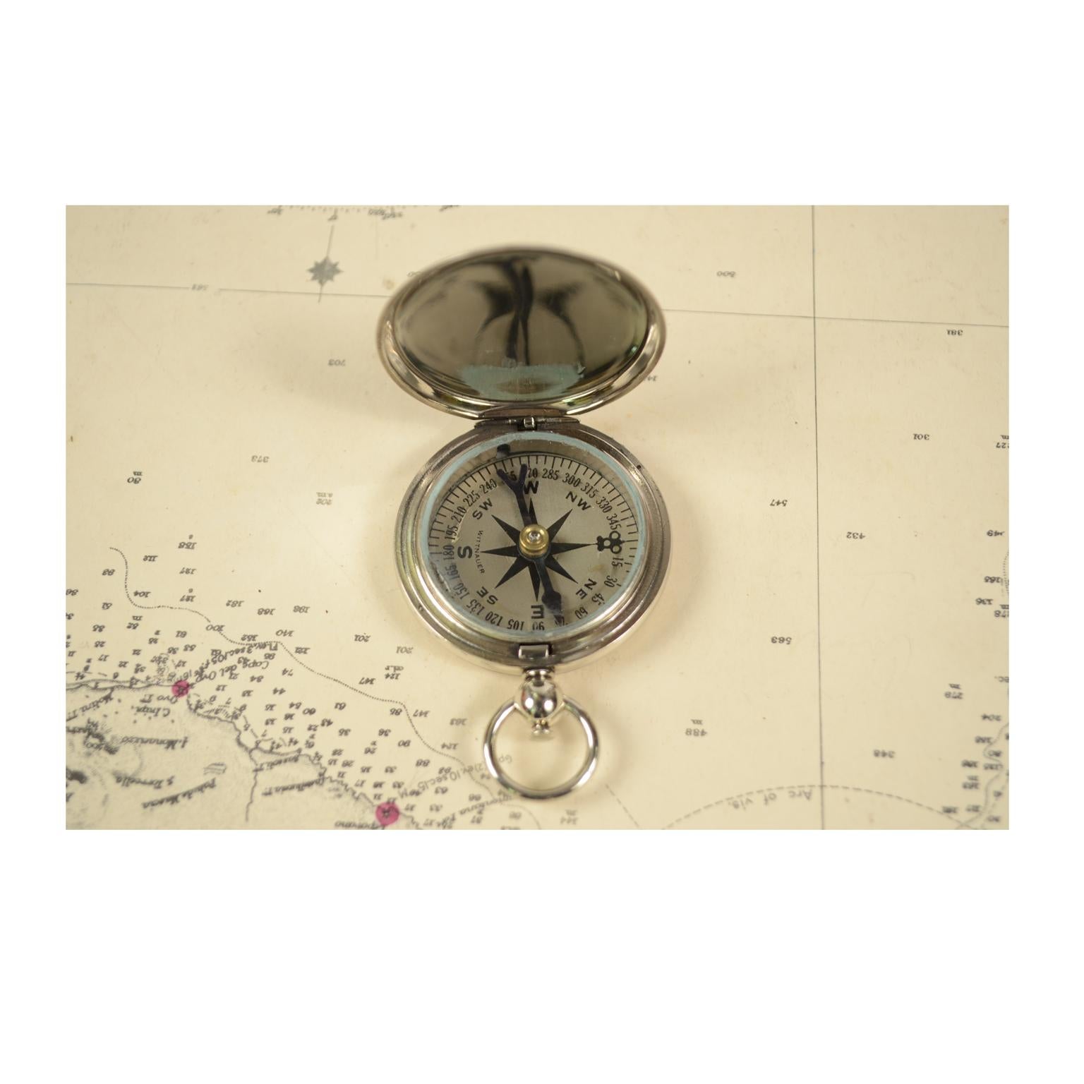 Pocket compass, chromed brass, in the shape of a pocket watch, used by American aviators during the Second World War, compass card with eight winds complete with goniometric circle. The compass is equipped with a lid with snap closure and a release