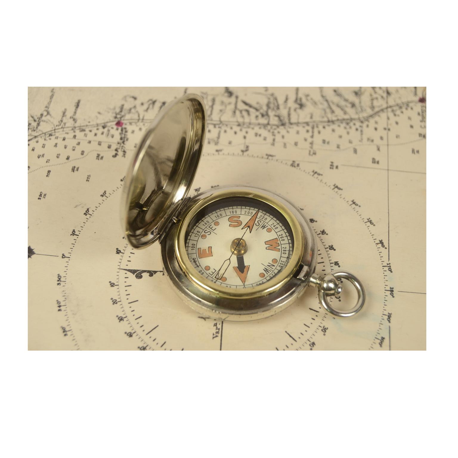 Pocket compass used by the officers of the British Navy during the First World War, made of chromed brass in the shape of a pocket watch. The compass is equipped with a lid with snap closure with release button inside the ring. Eight wind compass