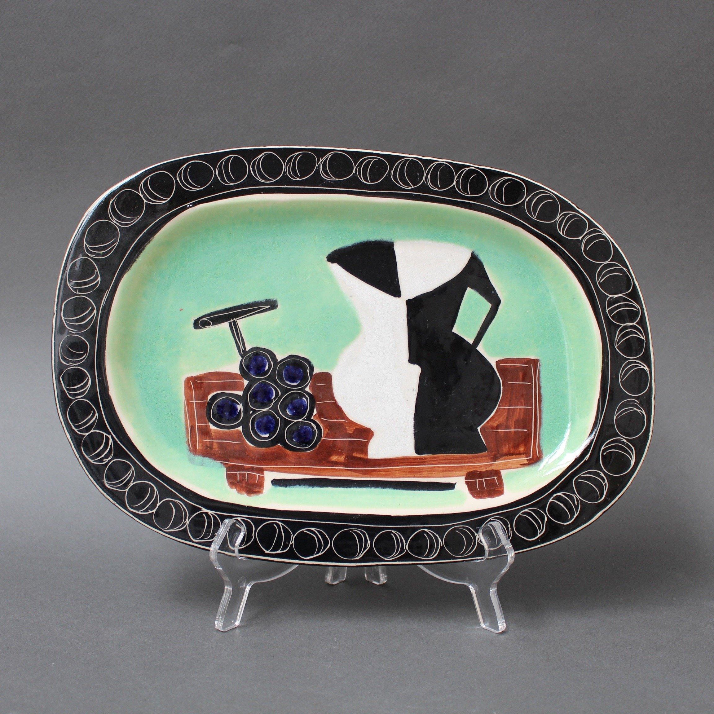 Plat décoratif en céramique Poët-Laval par Jacques Pouchain, vers les années 1950. Ce plat très rare incorpore l'image d'un pichet à vin stylisé et d'une grappe de raisin sur une table rustique, comme dans une nature morte peinte par Picasso.