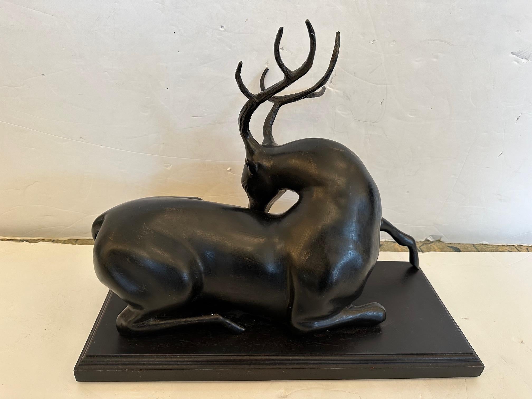 A beautiful gestural iron sculpture of a recumbent stag or deer with lovely outstretched leg.  Mounted on ebonized wood.