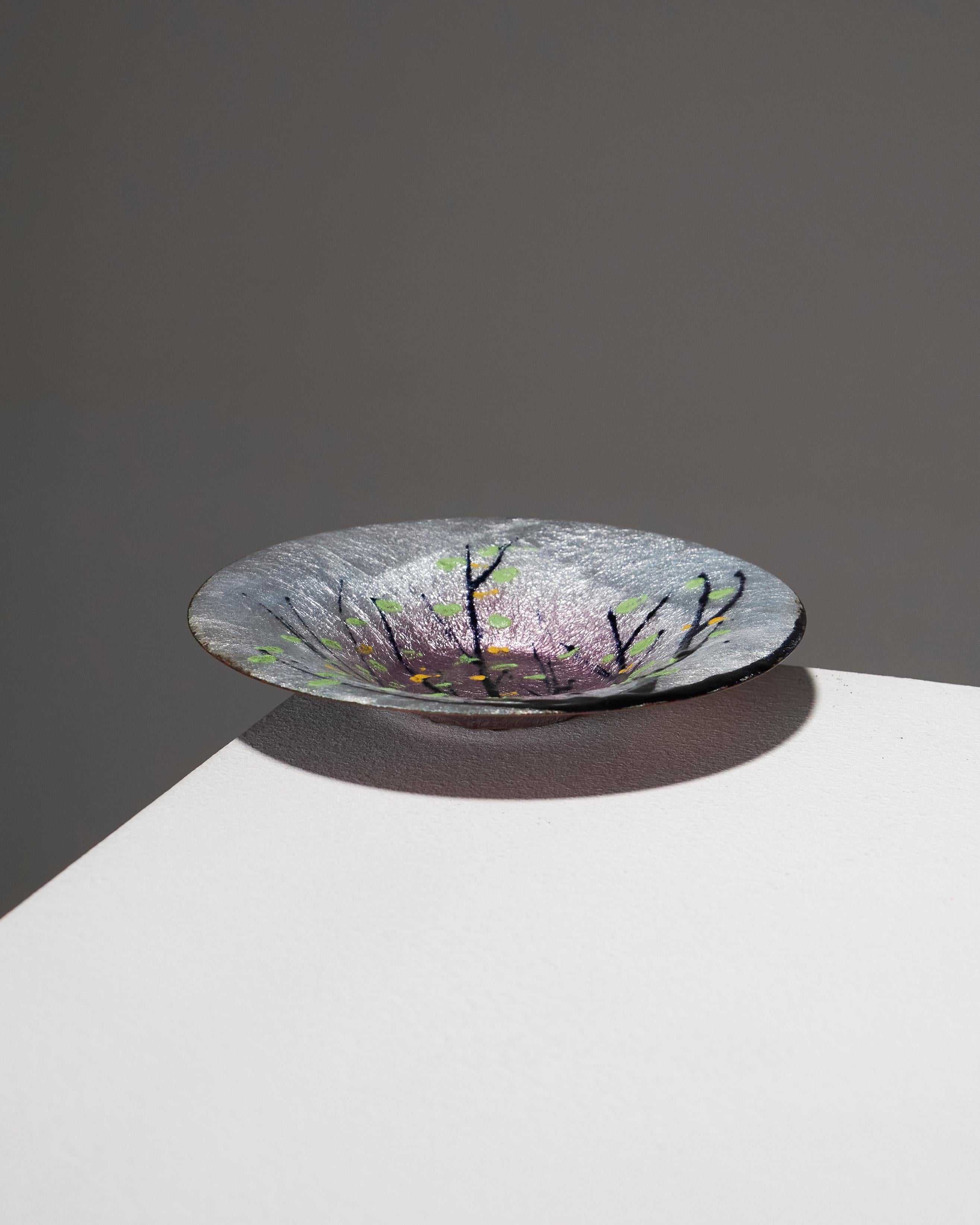 Limoges enamel bowl with a gradient white and mauve glaze, featuring a slightly crackled finish. The naturalistic and asymmetrical design depicts a tree with branches adorned with stylized leaves in vibrant colors of soft green and yellow. Beneath