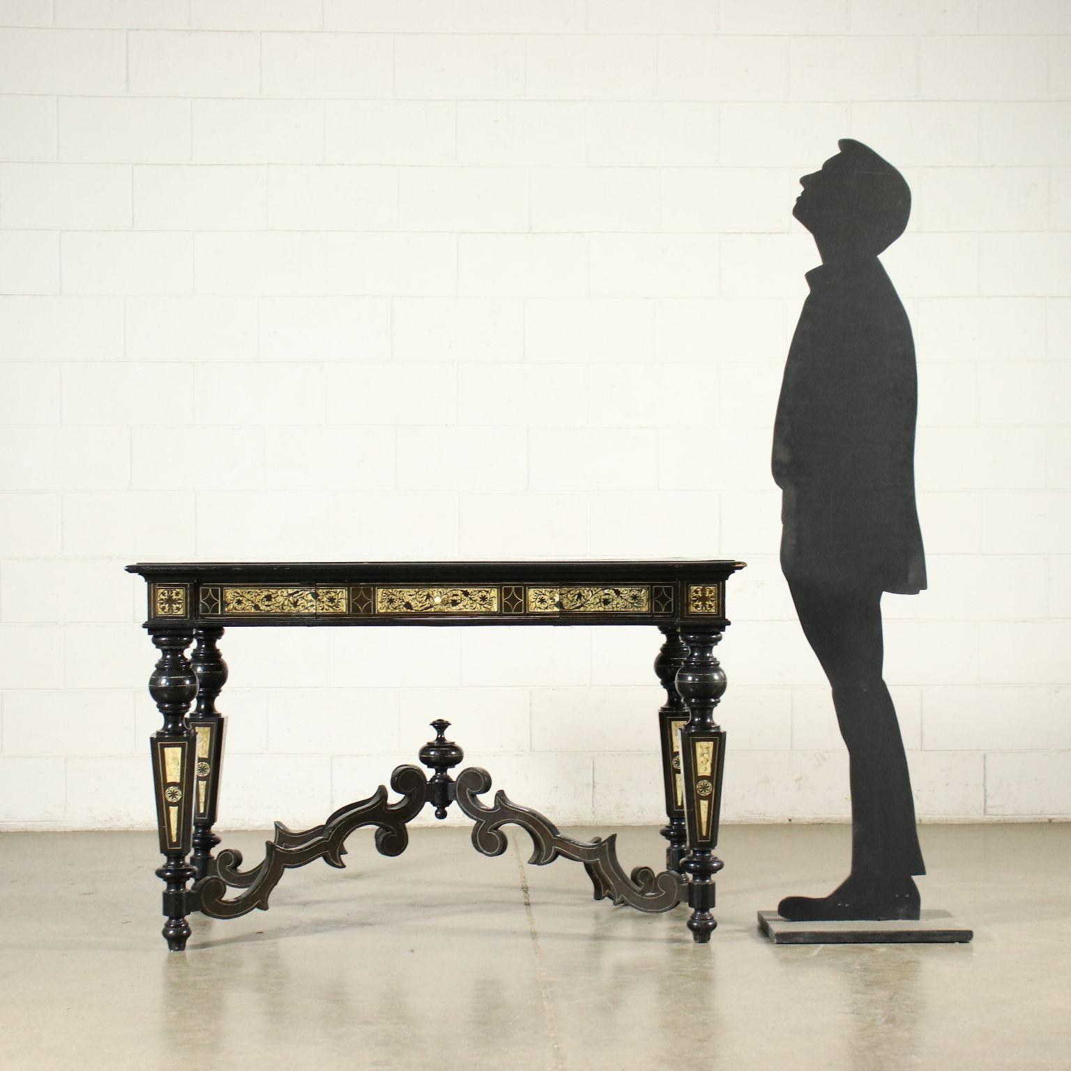 Desk supported by truncated pyramidal legs with feet and turned elements, connected by cross-bars carved in scrolls; there is a drawer in the undertop band. In ebonized wood, the desk is entirely inlaid in bone in the manner of Ferdinando Pogliani,