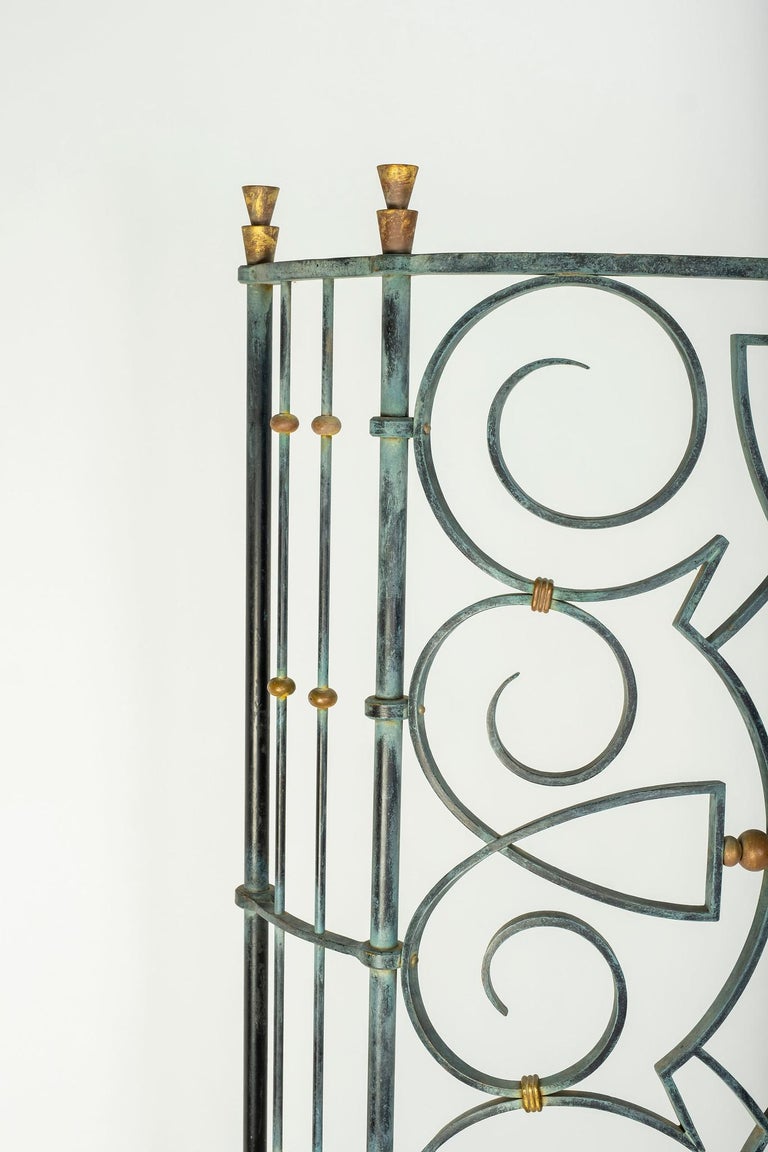 French Art Deco Gilbert Poillerat screen. A hand wrought iron two part screen with gracious sinuous curves, brass accent detail and verdigris coloring.

Overall dimensions:
Left panel 67.875