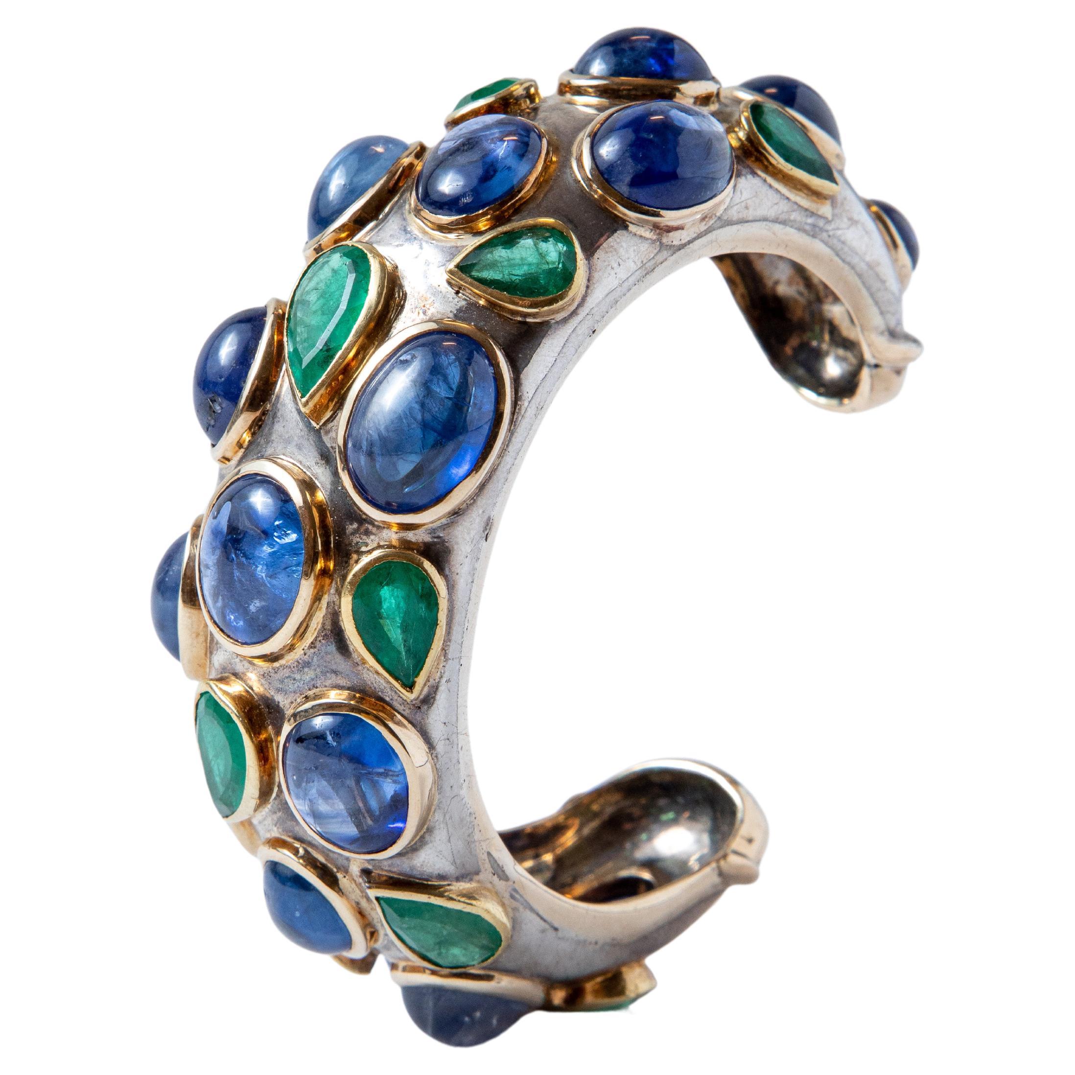 Bracelet in silver, features a multitude of cabochon sapphires and pear-shaped emeralds in 18k yellow gold setting.

Around 1980.

Unsigned, after a drawing and production by Michel Ermelin, jeweler and founder of the Poiray house, attributed to