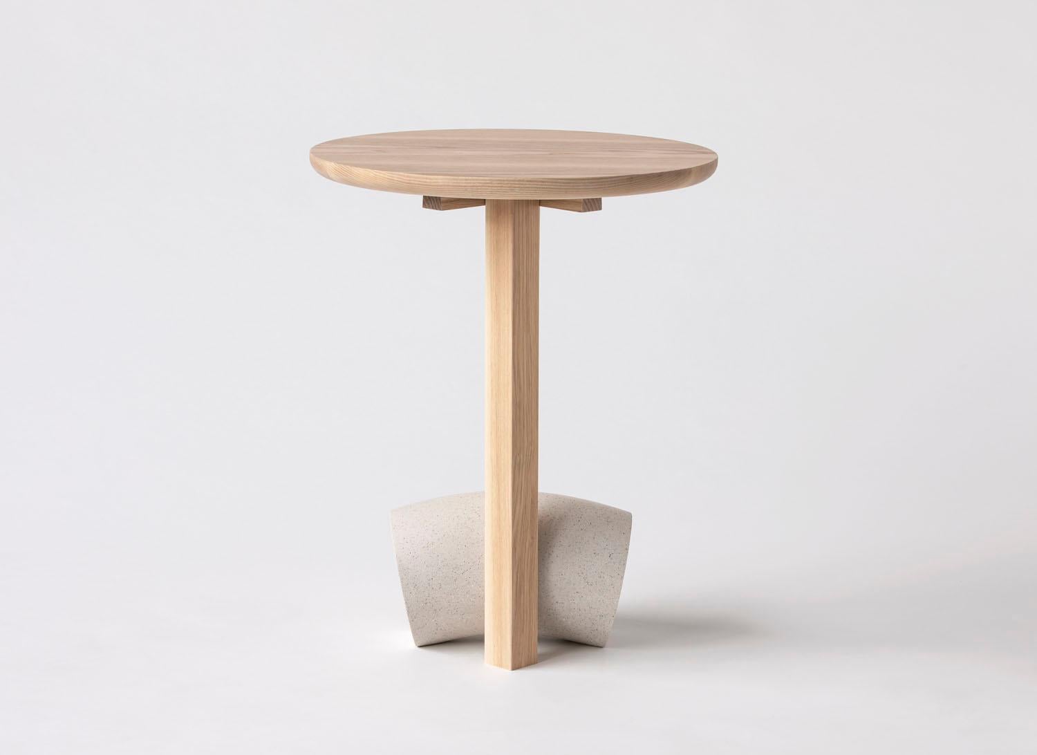 Die Poise-Kollektion umfasst eine Reihe skulpturaler Tische und Sitzmöbel, die die Wärme von Eschenholz mit der Schwere von Kunststein poetisch verbinden. Die Möbelstücke nutzen eine einzigartige Tischlermethode, um eine verblüffende und doch
