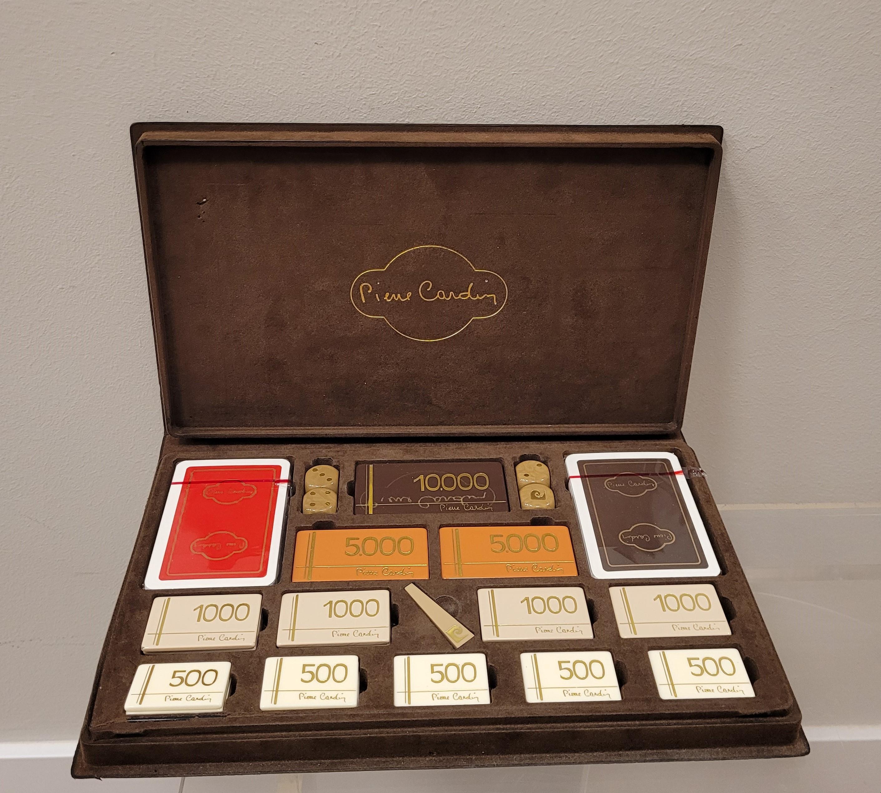 Vintage poker game, from the 60s or 70s, signed by the prestigious French designer Pierre Cardin. The box is made of brown velvet, and contains 2 new decks of cards and 48 tokens decorated with gold leaf, including the signature on each of them. In