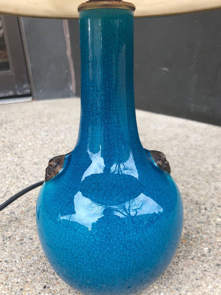 Deep blue crackle glaze lamp with small fu dog medallion decoration. Original shade has matching blue trim. Ceramic vase was originally made as a lamp base. Signed to underside 