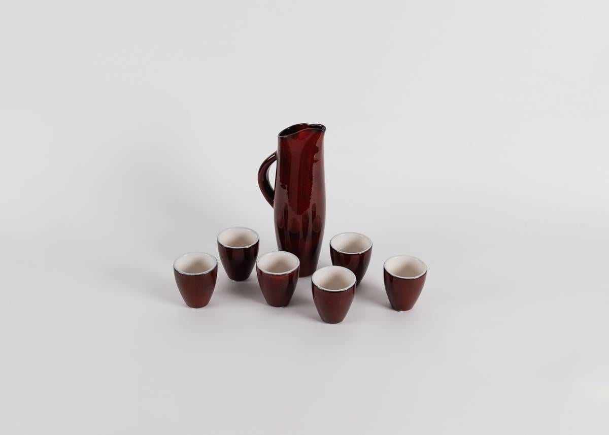 Pitcher and six matching cups with a sang de boeuf glaze.

Inscribed: 1972 Pol Chambost France
Monogramed under the cups.