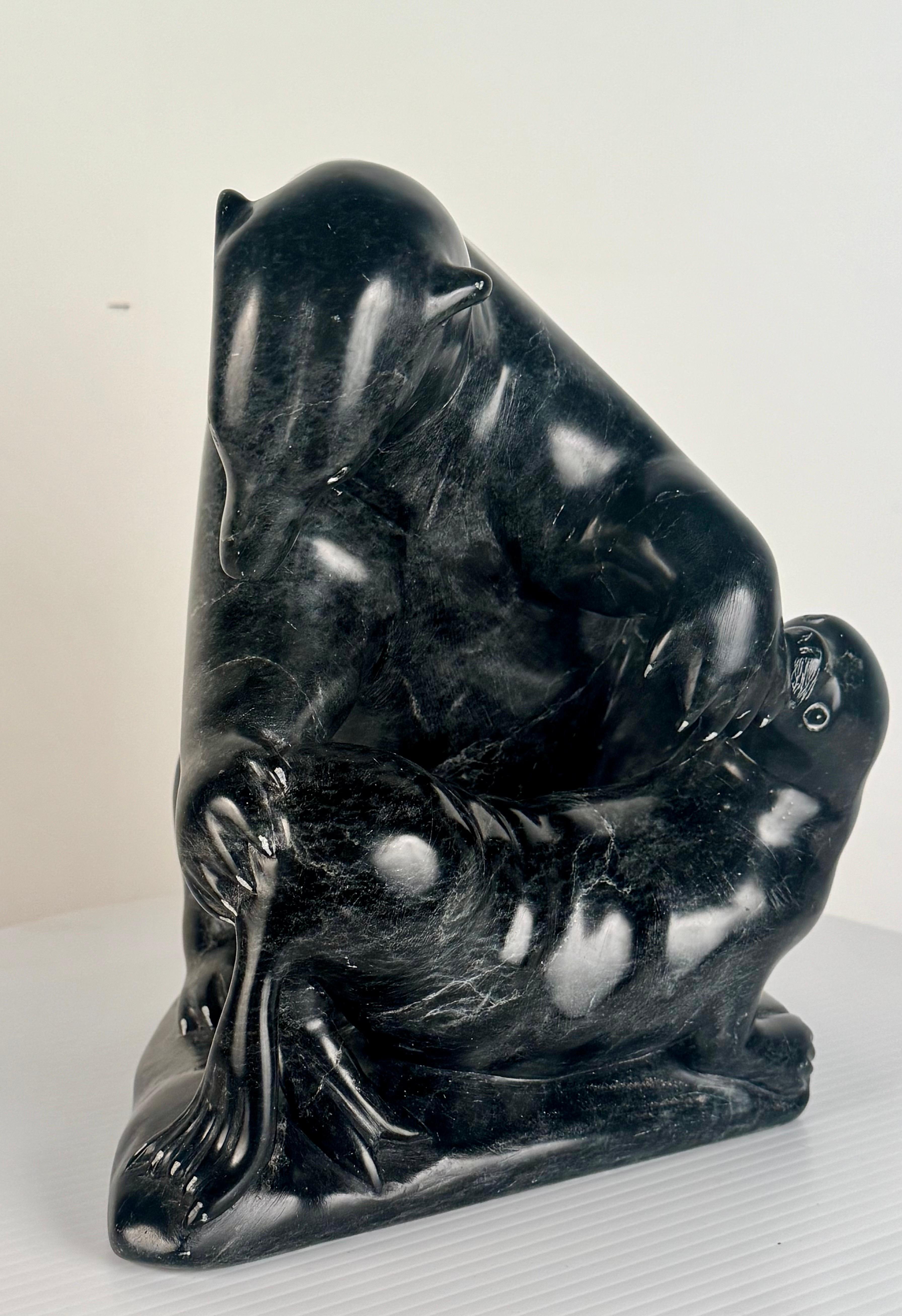 Esta talla de piedra verde representa a un oso polar que, tras acechar y capturar hábilmente a una foca, se dispone a matarla. Esta obra está hábilmente ejecutada, tanto técnica como artísticamente, por el artista Joanasie Jack Ittukalak, nacido en
