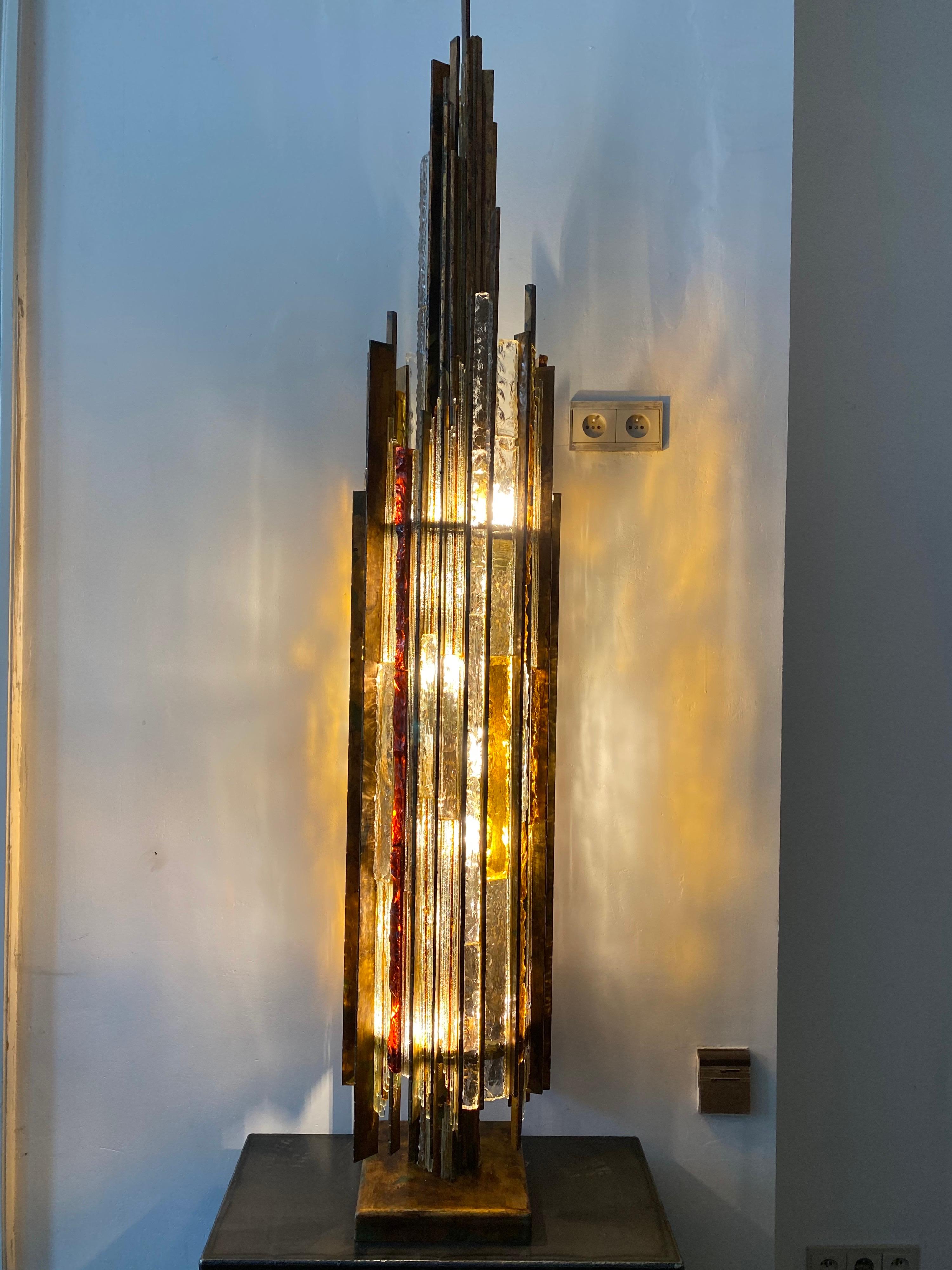 The floor lamp made by Albano Poli with artistic hammered glass and cast iron bronze base is hard to find. Albano Poli determined to make unique lamps that could shape light through mixed warm glass colors and shadows. These compositions, bronze and