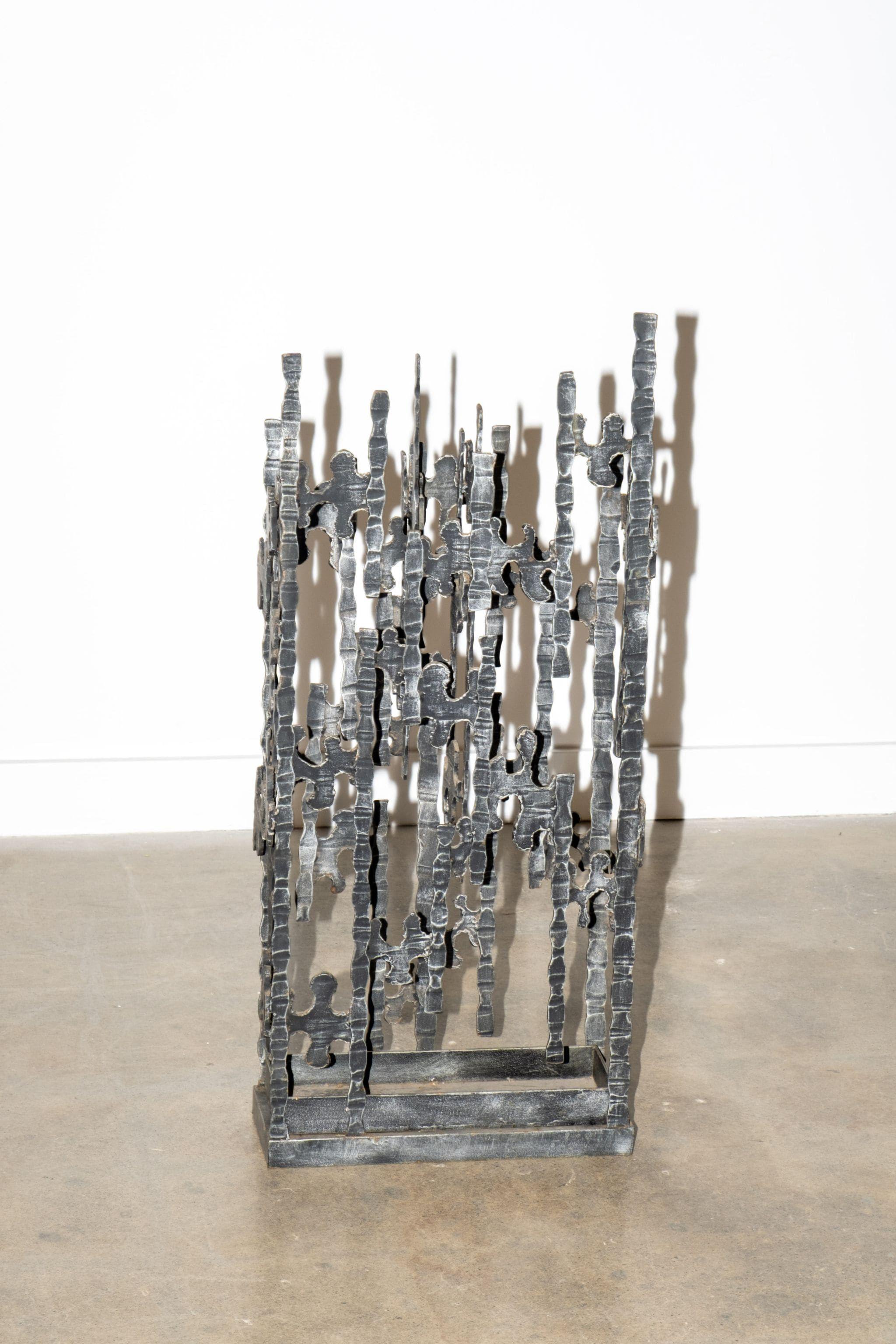 Avec ses lignes acérées et son poids sculptural, ce porte-parapluie de style Brutalist apporte une présence sérieuse à votre entrée. Fabriqué en fer avec une finition brute, coupée au chalumeau, il ressemble plus à une œuvre d'art abstraite qu'à une