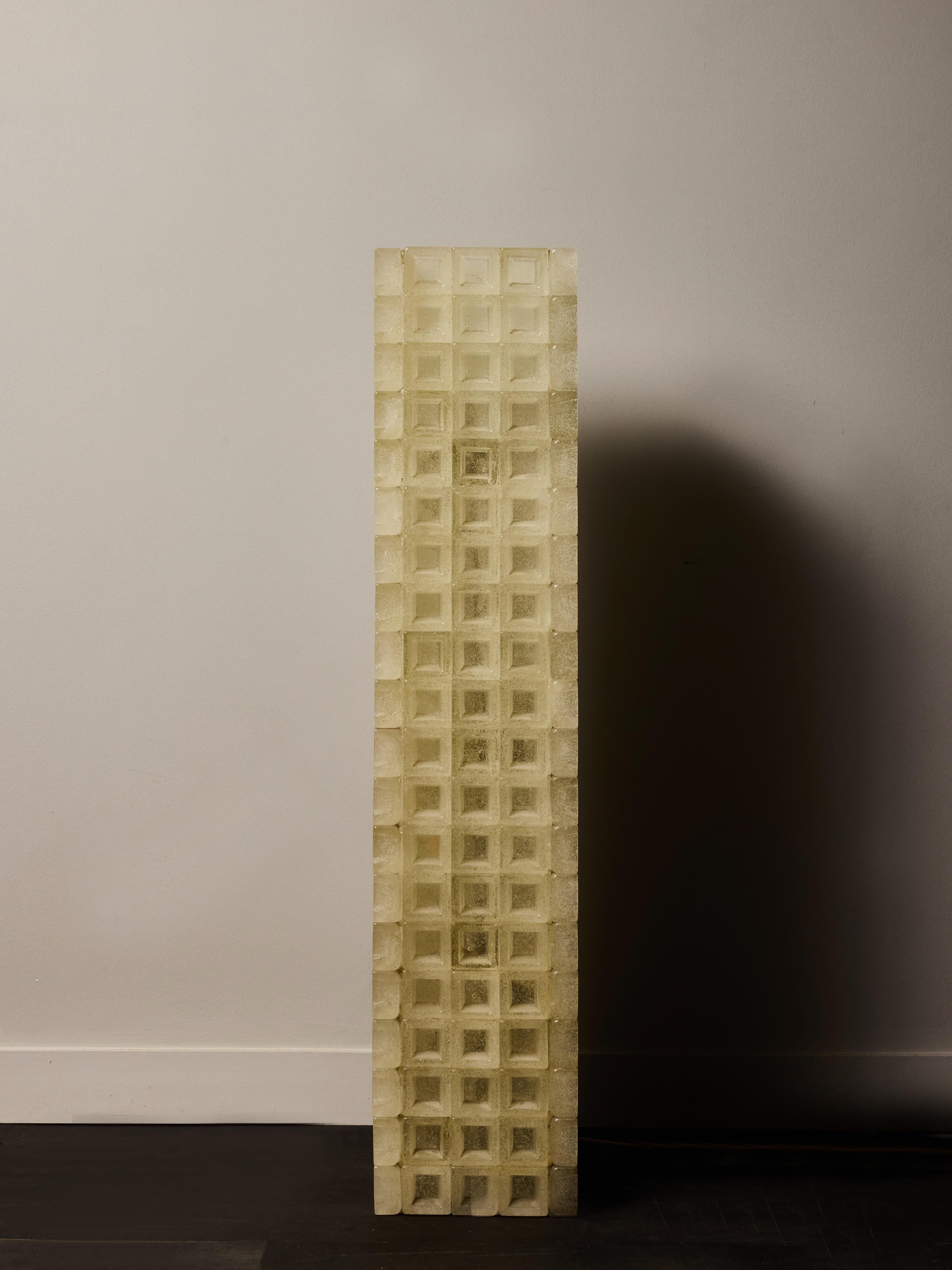 Lampadaire sculptural saisissant de Poliarte composé d'une haute tour monolithique de modules en verre moulé fabriqués à la main et disposés selon une grille rythmique. Chaque cube de verre est caractérisé par la surface texturée caractéristique de