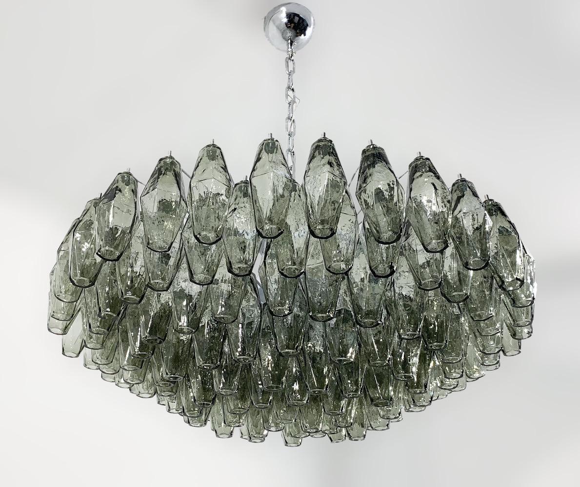 Araña moderna italiana con cristal de Murano de forma poliedro / poliédrica gris ahumado, montada sobre marco de metal esmaltado blanco, al estilo de Venini y Carlo Scarpa / Fabricada en Italia por Fabio Ltd
Diámetro: 32 pulgadas / Altura: 11