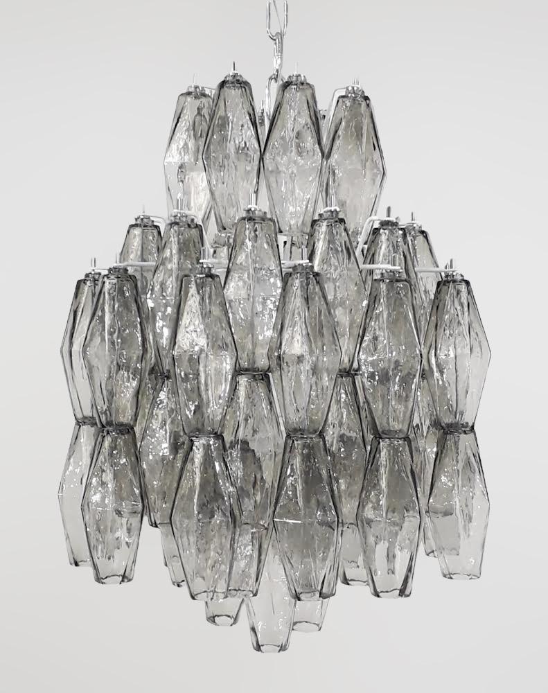 Lampadario moderno italiano con vetro di Murano a forma di poliedro grigio fumo, montato su una struttura in metallo smaltato bianco, nello stile di Venini e Carlo Scarpa / Prodotto in Italia da FABIO LTD
Diametro: 16 pollici / Altezza: 17 pollici