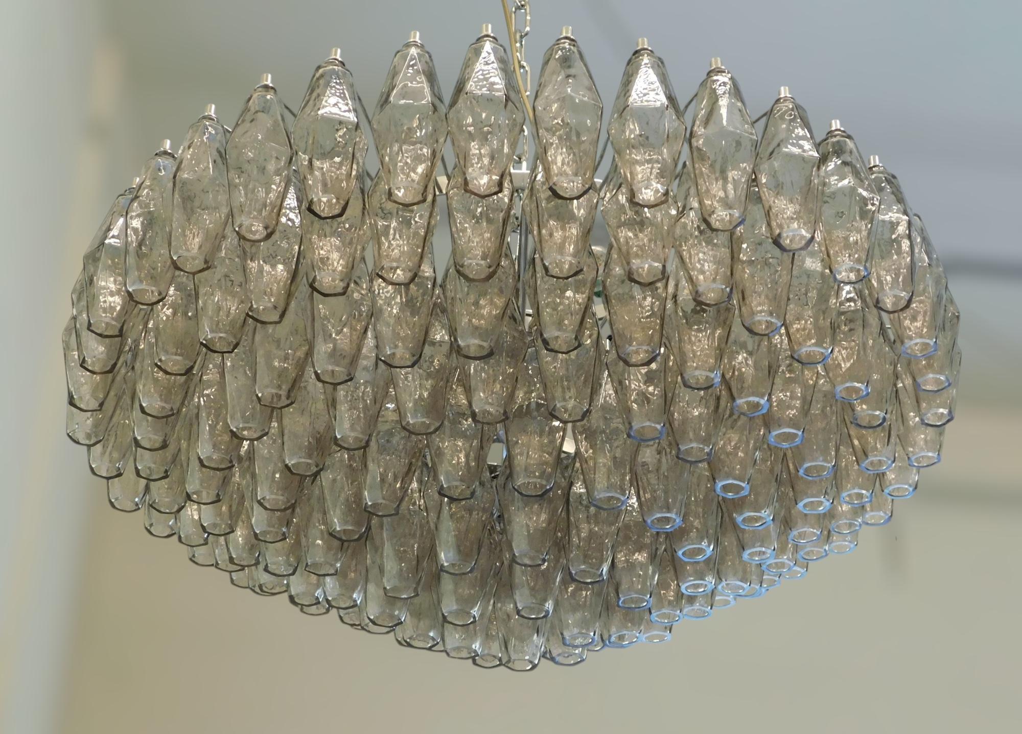 Lampadario moderno italiano con vetri di Murano a forma di poliedro fumé, montati su una struttura in metallo cromato, nello stile di Venini e Carlo Scarpa / Made in Italy
Diametro: 33,5 pollici / Altezza: 16 / Altezza totale: 35,5 pollici, compresa