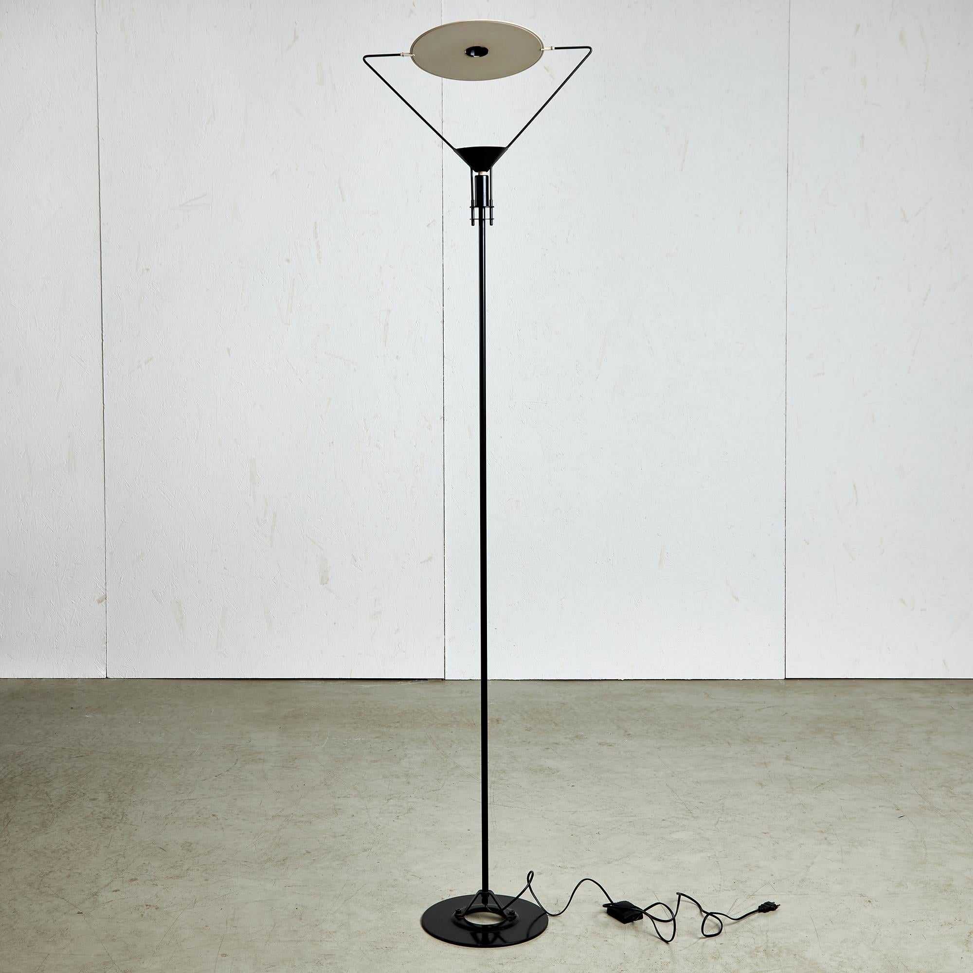Geometrical forms and minimal design, the Artemide 'Polifemo' is a slim black metal floor lamp, with a triangular top and a white round metal plate. Designed by Carlo Forcolini for Artemide in 1980. A triangular support holds the circular reflector