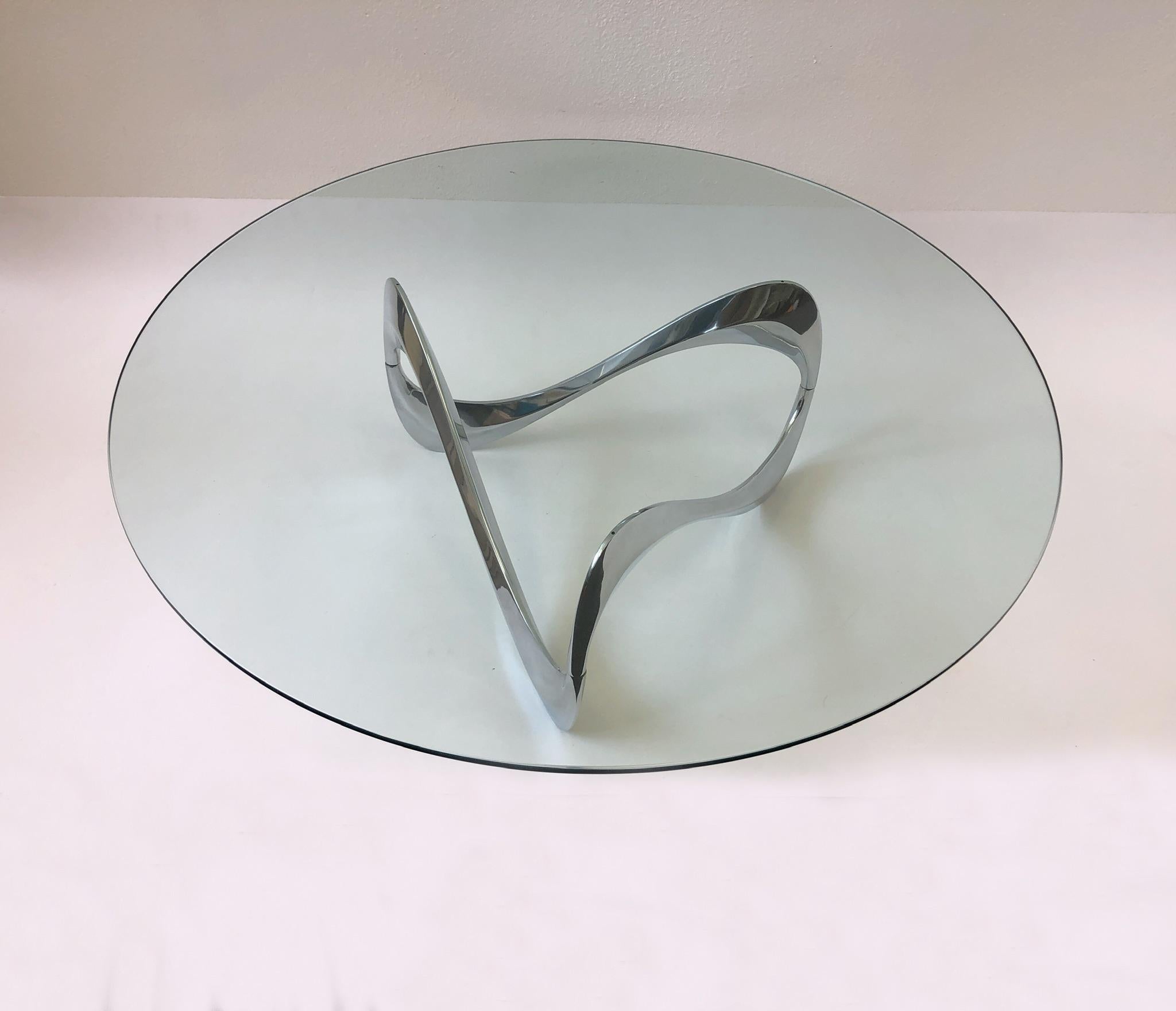A sculptural polish aluminum and glass ‘Snake’ cocktail table. Design by German designer Knut Hesterberg in the 1960s. New 48” diameter 1/2” thick glass top. The base is newly professionally polished, but still show some age (see detail photos). The