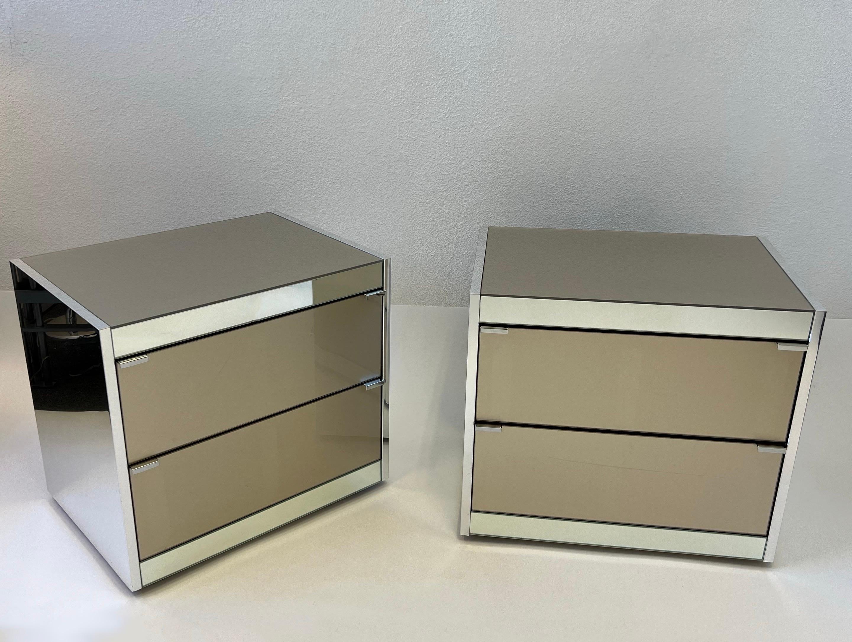 Pair of 1980s polish aluminum and glass, two drawer nightstands by Ello Furniture. 
The sides are polish aluminum, the tops and front drawers are champagne colored glass. 
In original vintage condition shows minor wear consistent with age (See