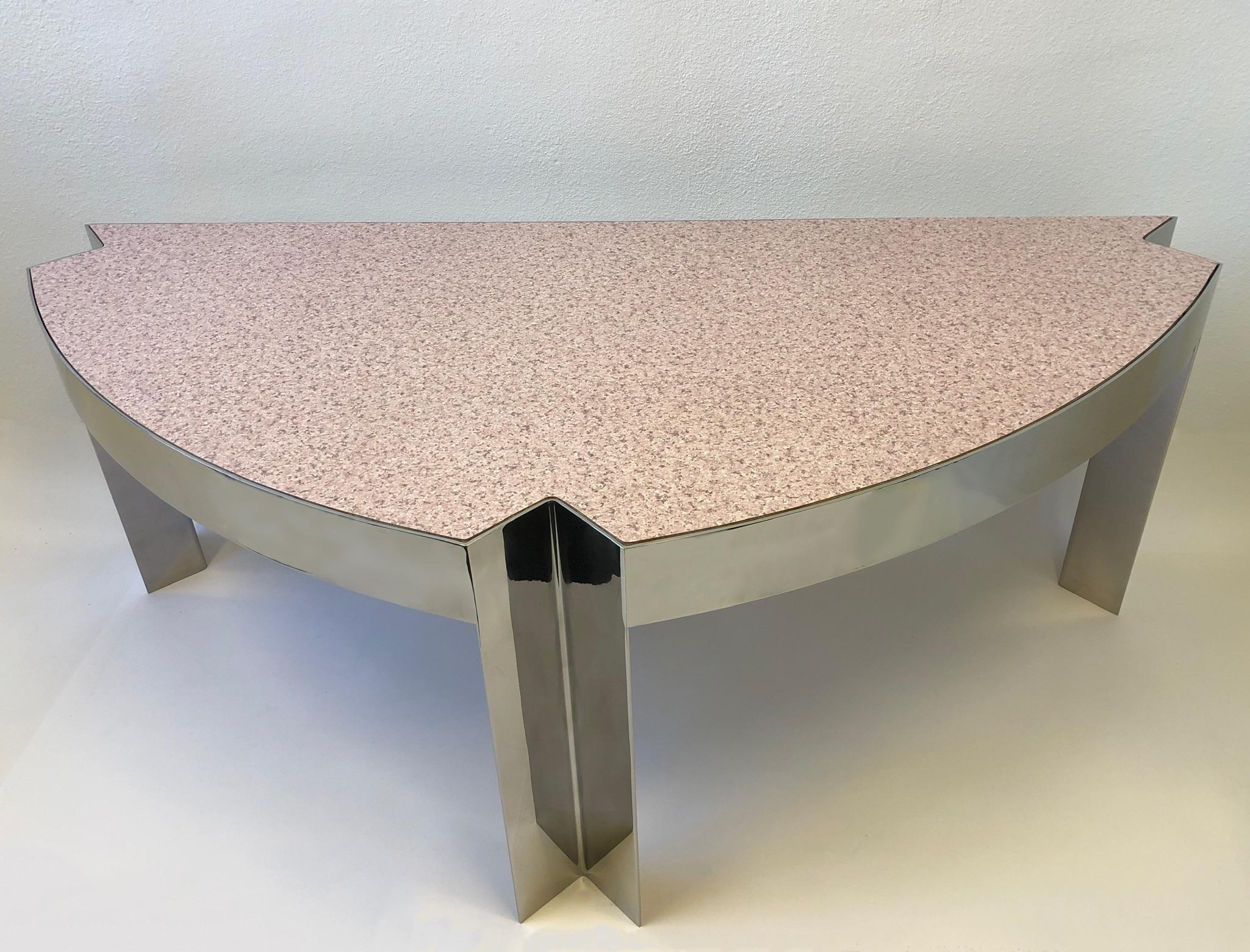 Glamorous 1970’s polish aluminum and faux pink granite Formica top “Mezzaluna” desk by Leon Rosen for Pace Collection. 
Constructed of solid polished aluminum with an inset faux pink granite Formica top. 
It has no drawers, so it can be used as a