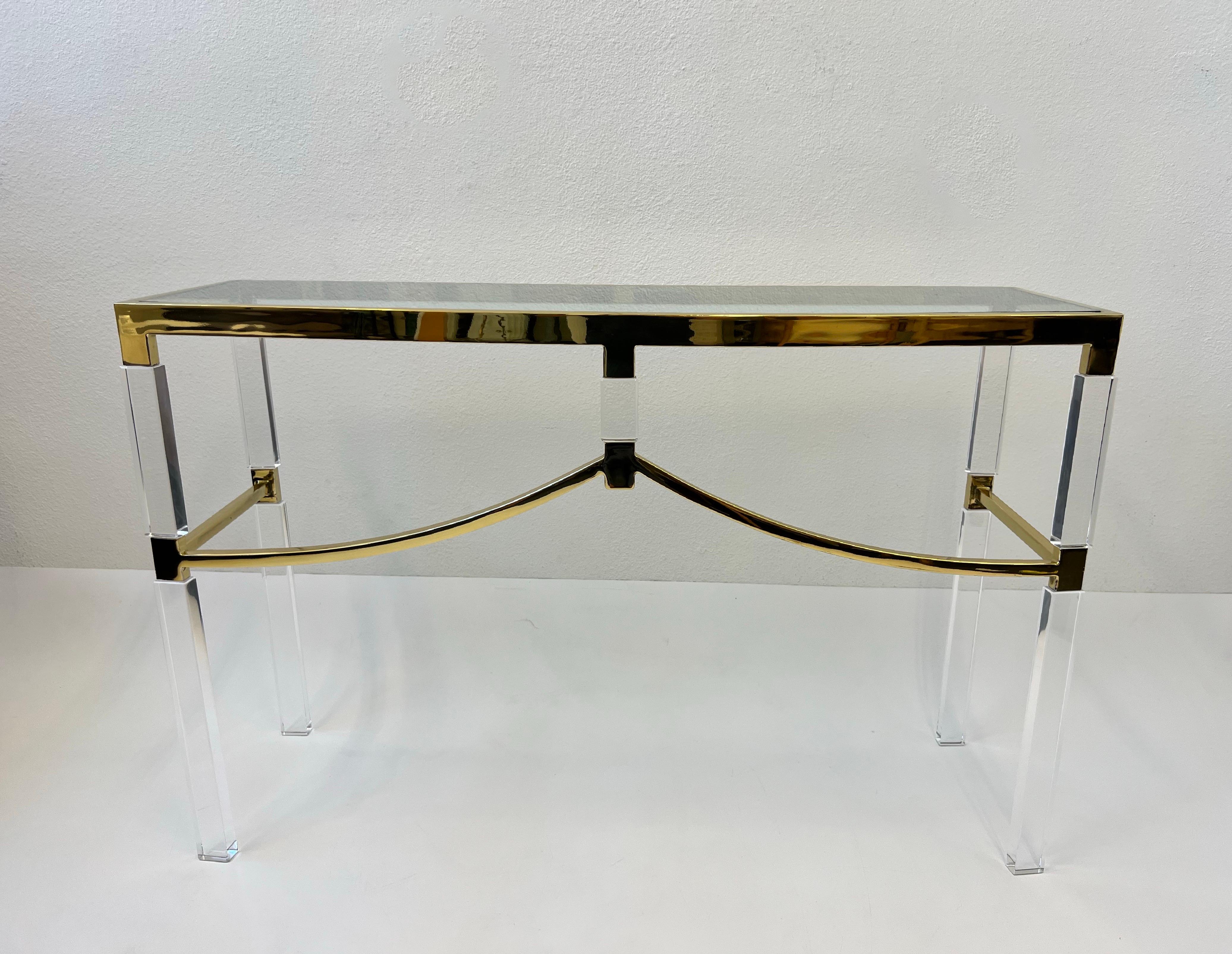 1970s polish brass and clear lucite with a glass top “Regency” console table by renowned American designer Charles Hollis Jones. 
The acrylic has been newly professionally polished, the brass shows minor wear consistent with age. New glass top.