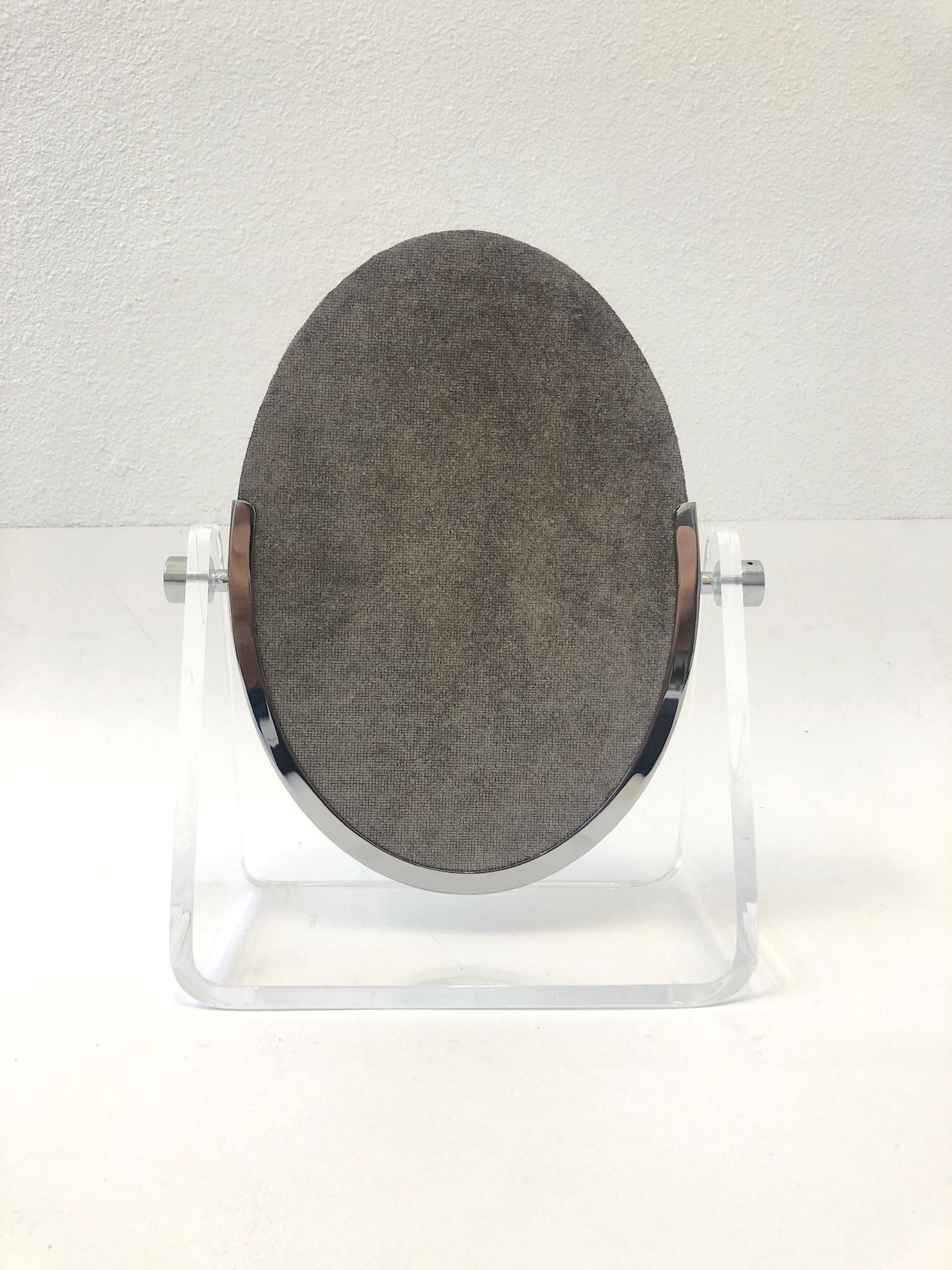Glamorous 1970’s Lucite and polish chrome vanity mirror by American renowned designer Charles Hollis Jones. 
New mirror with metallic light mocha brown suede back. 
Measurements: 12.75” wide, 6” deep and 15.75” high.