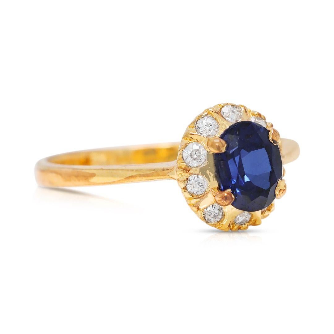 A delicate fusion of elegance and brilliance, this 18K yellow gold ring features a 0.2ct oval-cut sapphire, radiating a rich dark blue hue, embodying sophistication and timeless beauty. Accentuating its allure, 10 round brilliant-cut natural