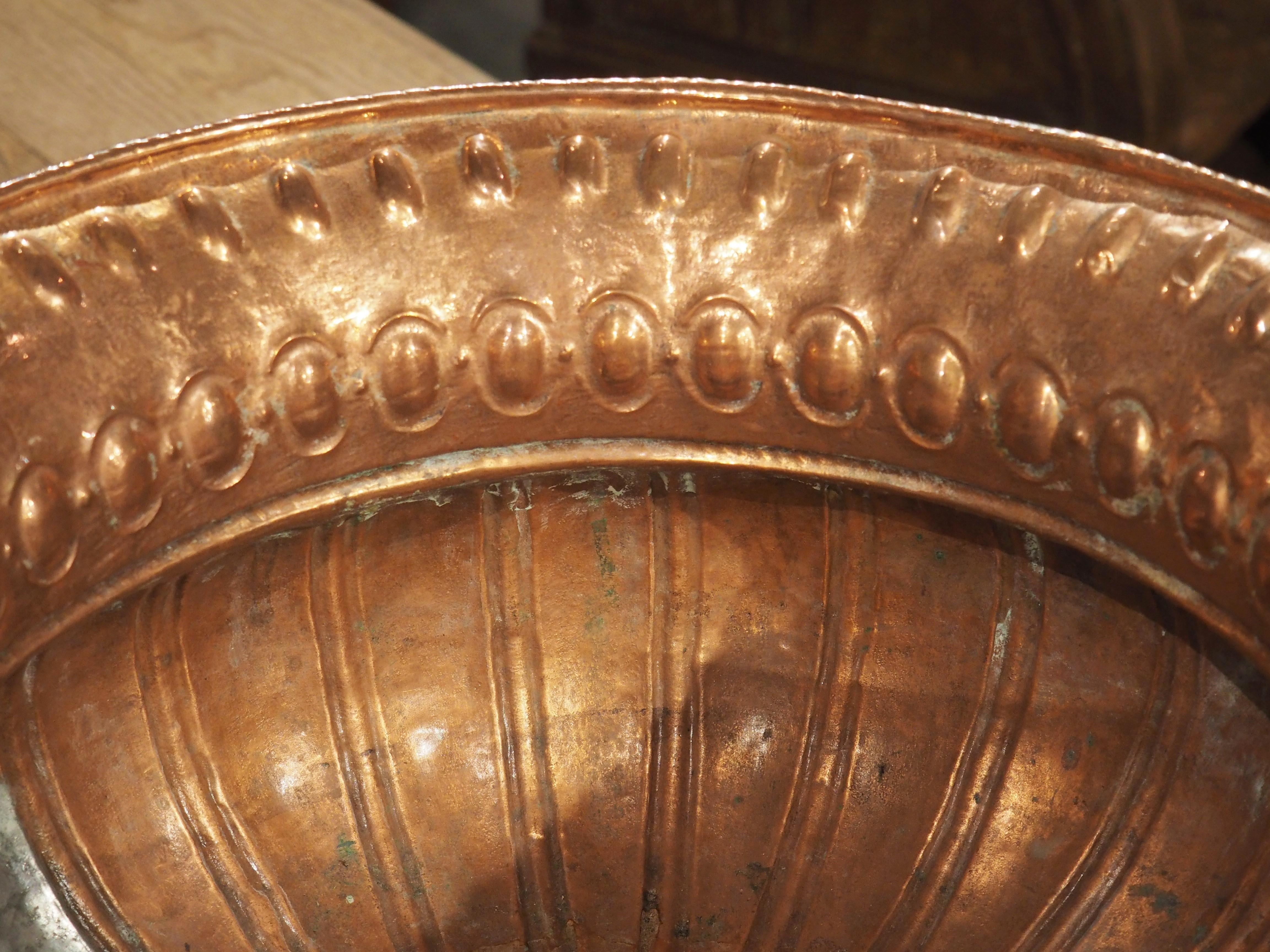 Known as a rafraichissoir, this beautifully polished copper vessel has been hammered using both repousse and chasing metalworking techniques. Beneath the thinly rolled rim is a repetitive border of widely space recessed lobes on the neck, just above