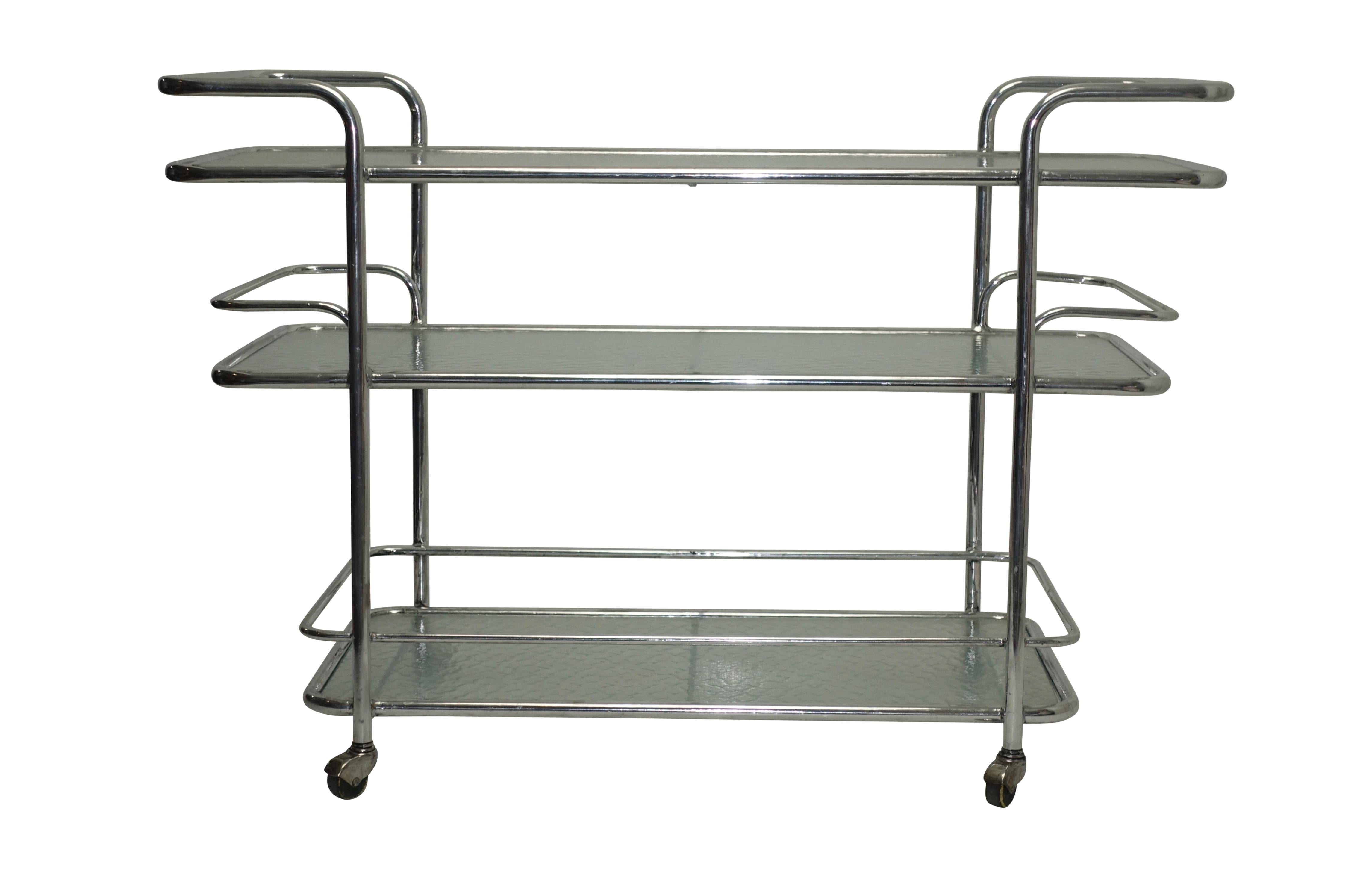 A three-tier polished aluminum serving cart or drinks cart with textured glass shelves on rolling wheels. American, circa 1950.