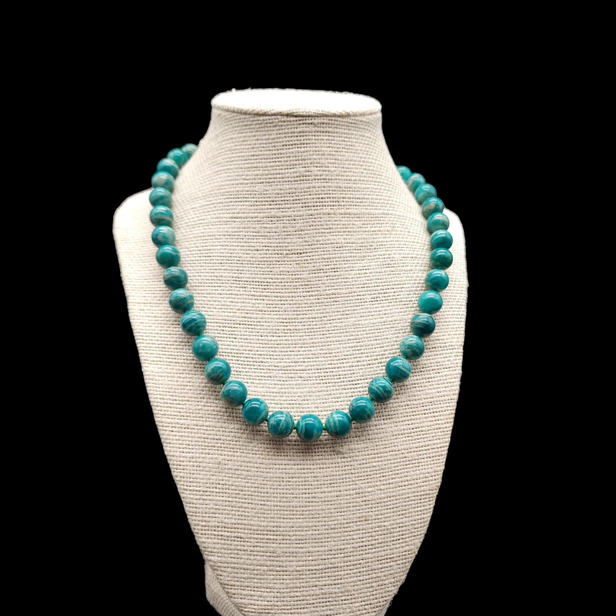 This vintage necklace features polished amazonite beads in a beautiful shade of blue-green. The beads are strung on a secure rope and connected with a sterling silver clasp. The necklace has a collar length, making it perfect for adding a pop of