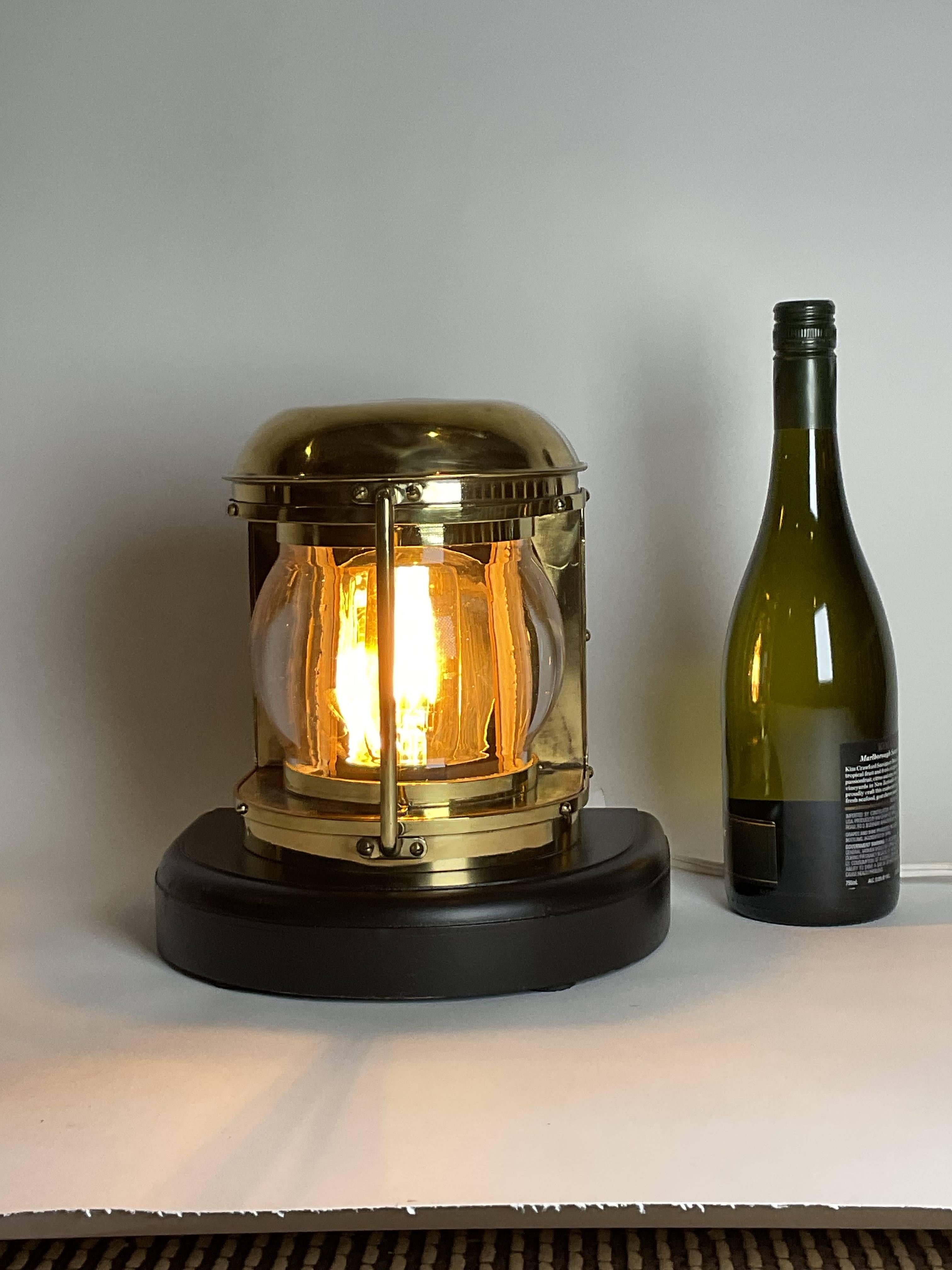 Highly polished boat lantern with thick bulbous glass lens. This has been meticulously polished and lacquered. Mounted to a thick wood base with  dark rich finish. Wired with a vintage bulb. by Japanese maker. Exceptional item. Circa 1960.

Weight: