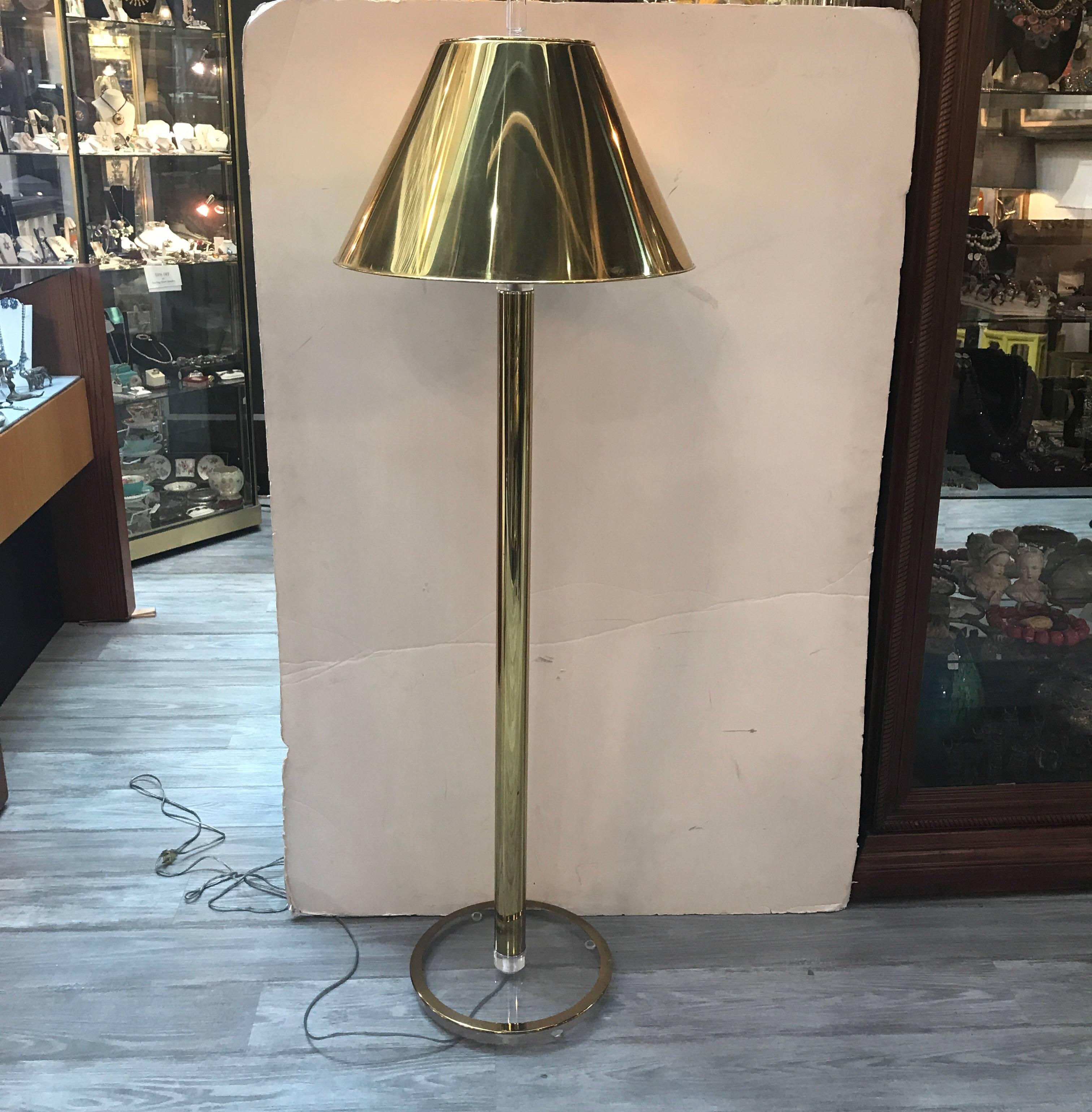 Chic Mid-Century Modern Hansen style polished brass and Lucite floor lamp with polished brass shade. The tapered shade above a simple cylinder shaft with Lucite brass trimmed base. Please contact us for a shipping quote as we can have this sent UPS