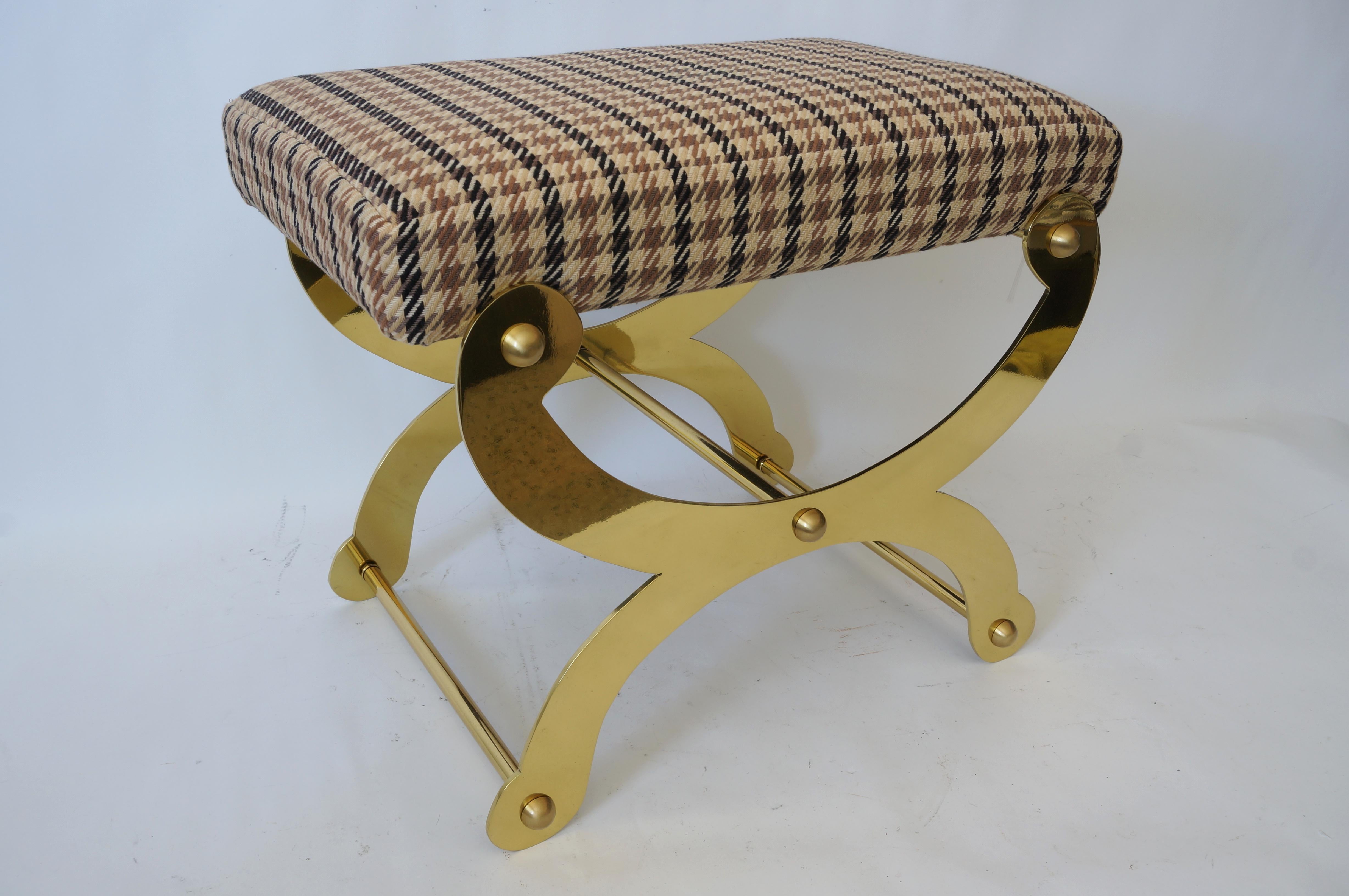 This stylish and chic campaign style, curule-form bench has been professionally polished and lacquered and reupholstered in a woven hounds-tooth fabric.

Note: The piece is all solid brass and polished, and the photos show dark reflections from