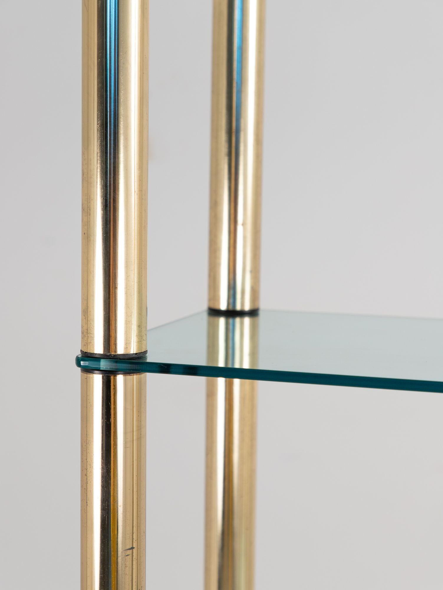 A sophisticated polished brass étagère from the USA, 1970s, featuring clean lines and timeless appeal. This piece is designed with multiple glass shelves, perfect for displaying books, decor, or collectibles. The brass finish offers a warm,