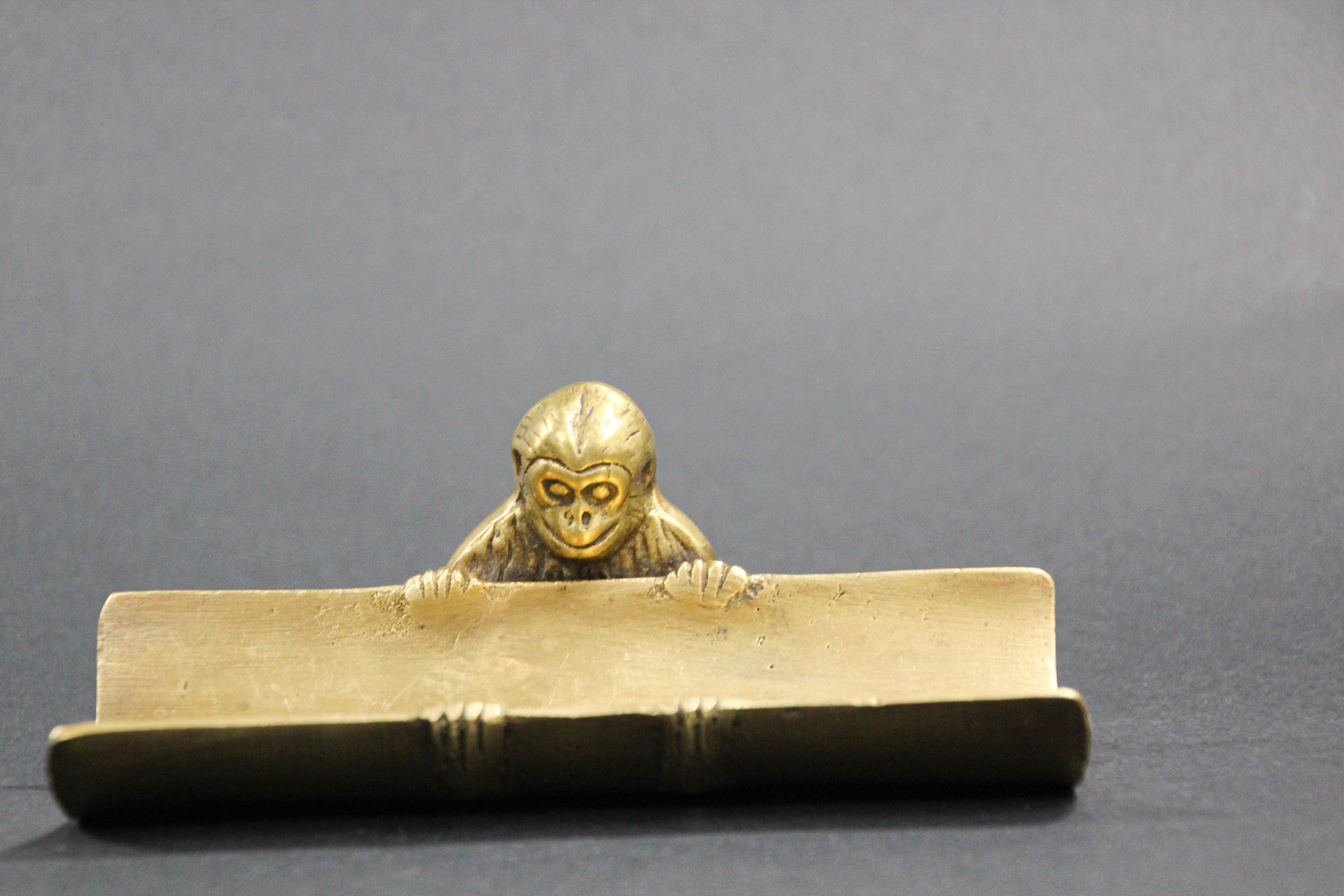 Vintage office desk polished brass monkey paperweight, pen tray holder or card holder, eye glass holder, catchall.
Handcrafted solid brass, Metal Art, Monkey is holding the tray on his feet and peeking over the top to see what’s inside. 
Tray is